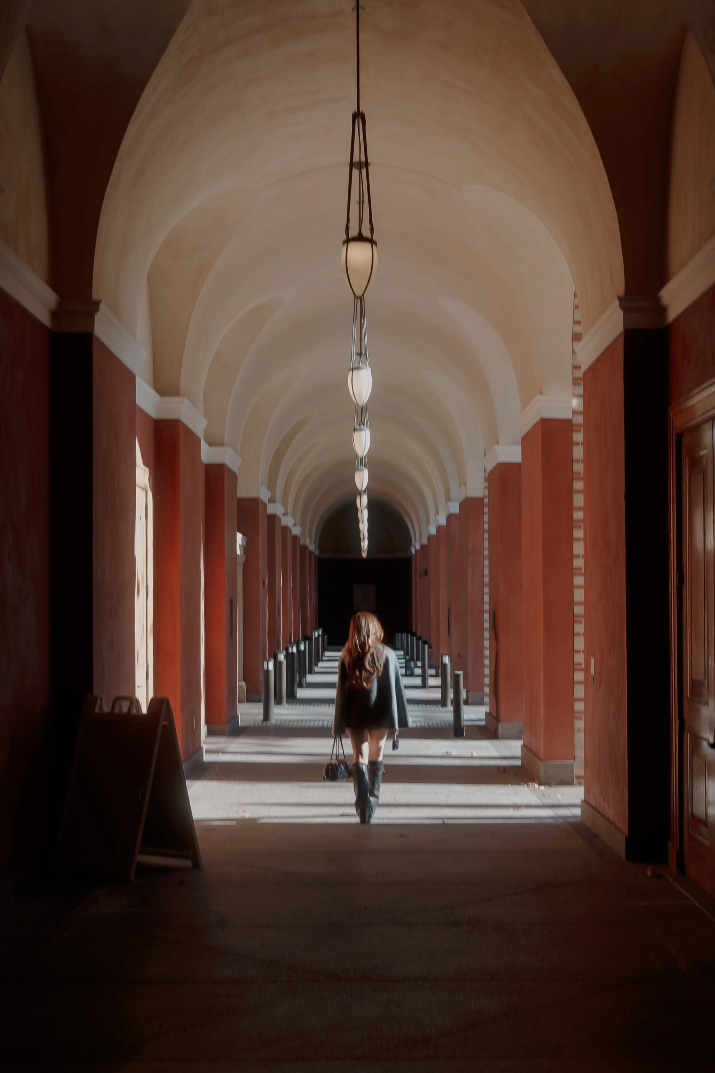 Fashion editorial portrait of a woman walking through an arched architectural walkway in natural light, photographed by Lei Photography Collective.