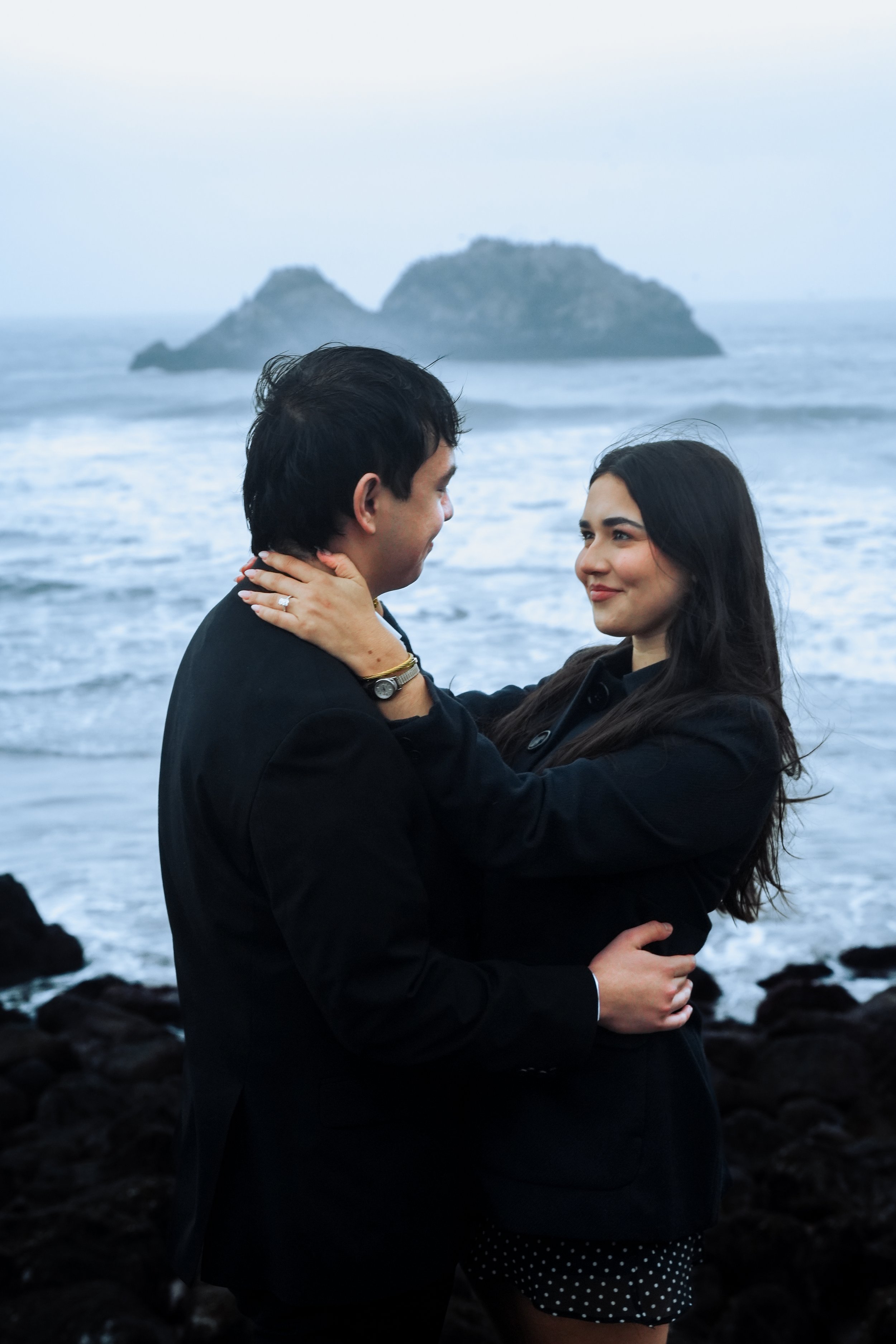 Couple holding each other during a natural light coastal couples session by the ocean in the Bay Area, photographed by Lei Photography Collective.