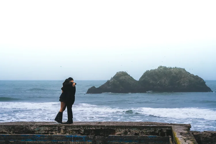 Couple embracing by the ocean, candid natural light