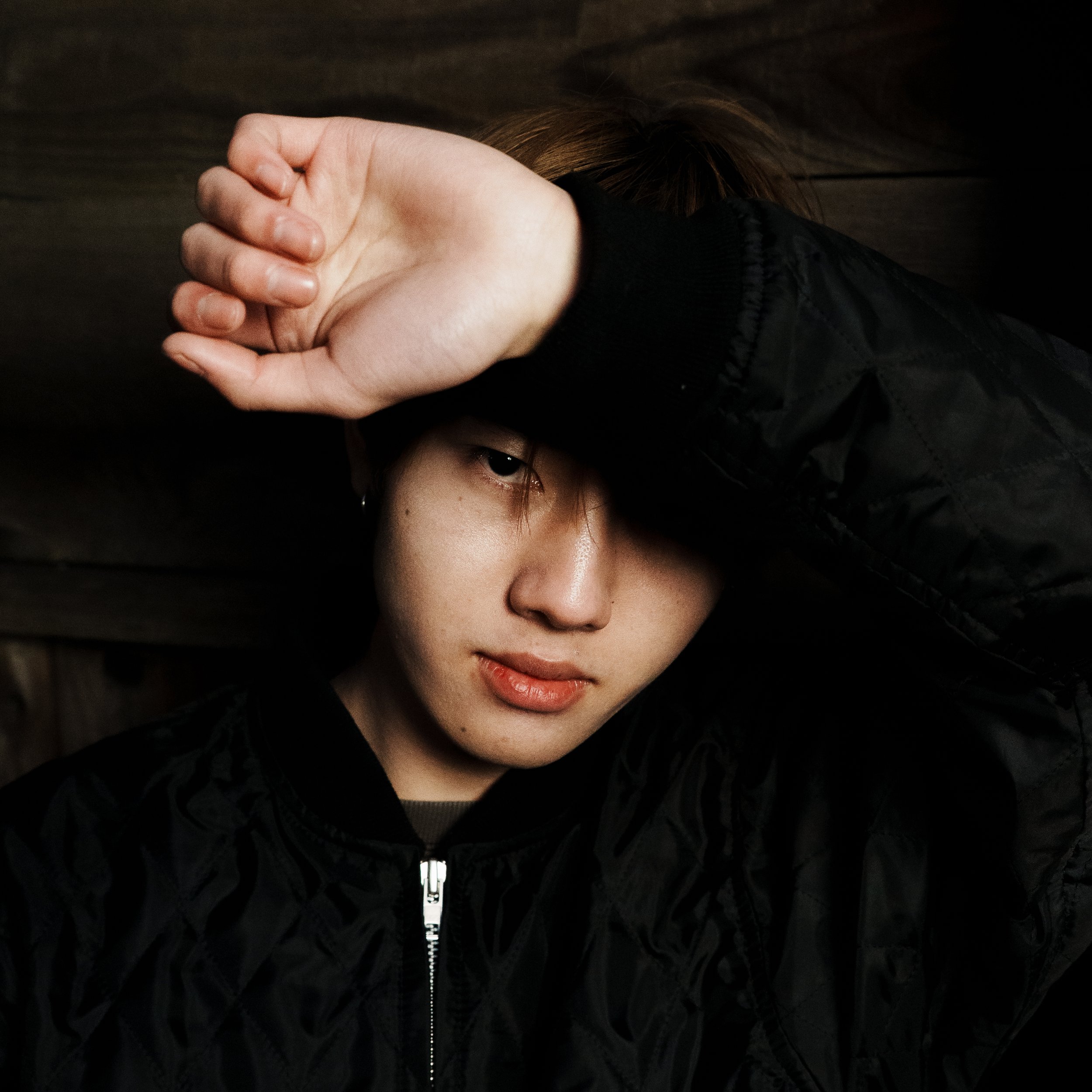 Moody fashion editorial portrait of a person partially shadowed by their arm, photographed by Lei Photography Collective.