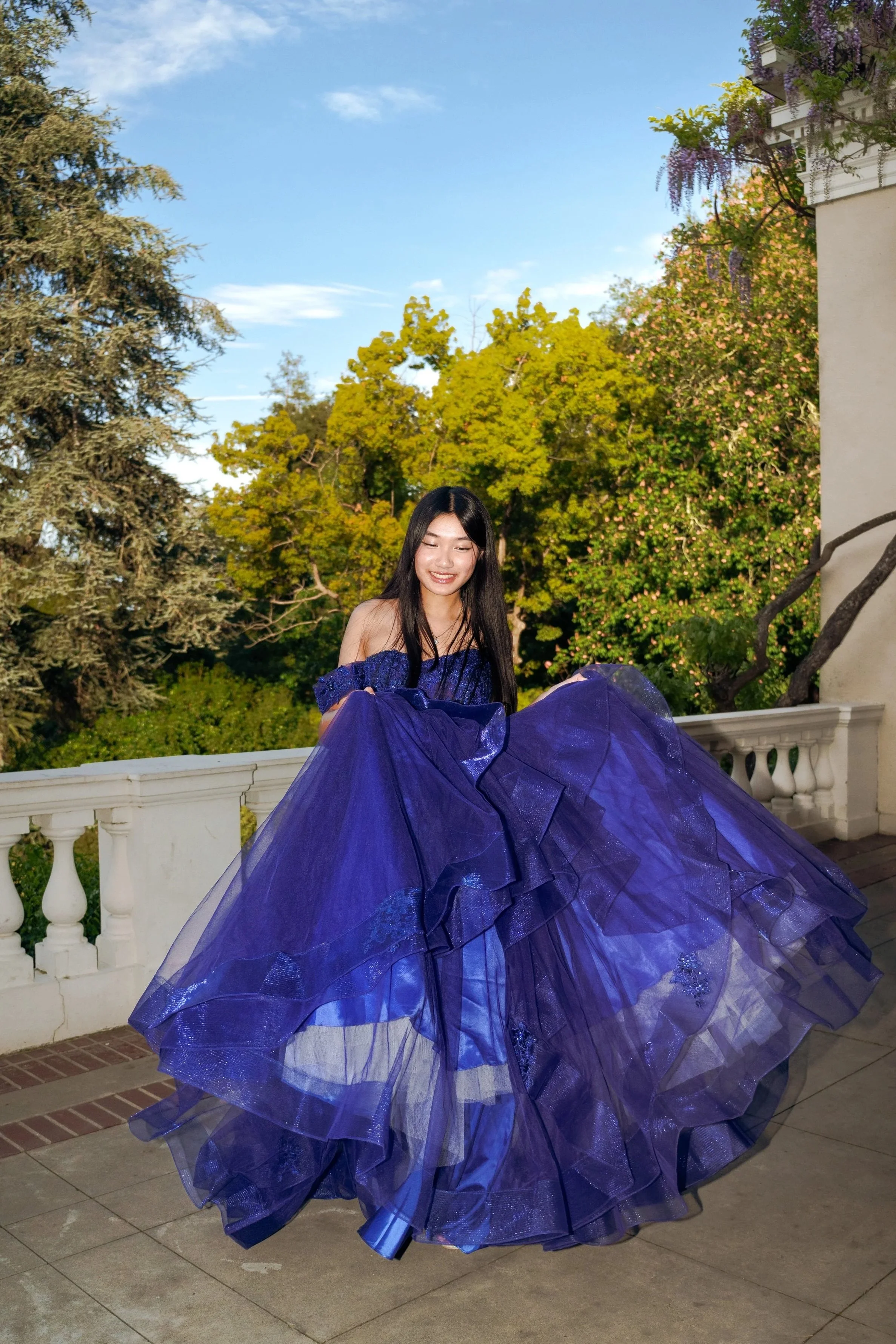 Fashion editorial portrait of a woman wearing a flowing evening gown outdoors, photographed in natural light by Lei Photography Collective.