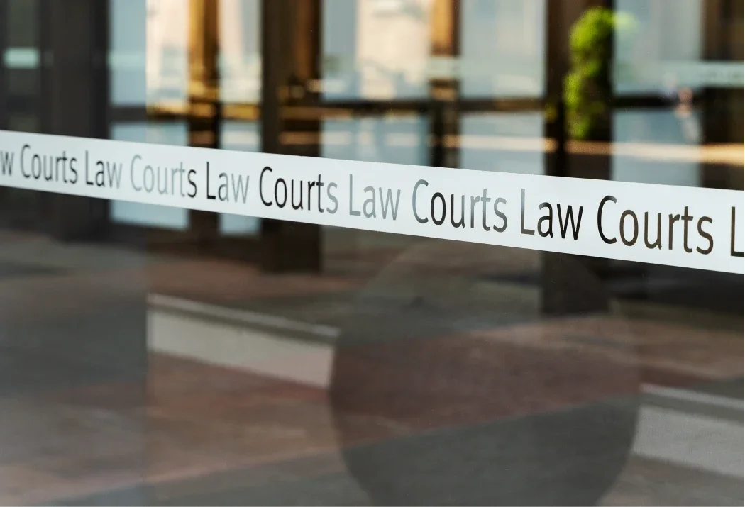 Glass door with a strip of tape labeled 'Law Courts' in front of a hallway or lobby area inside a courthouse.