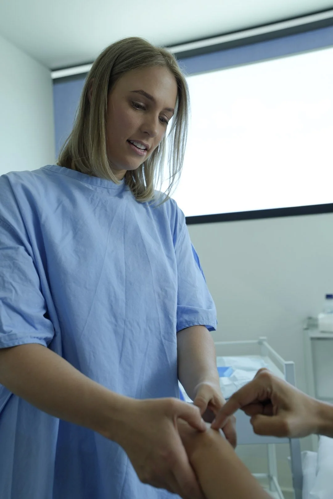 Person signing a consent form on a clipboard with a pen, with medical stethoscope on the table nearby.