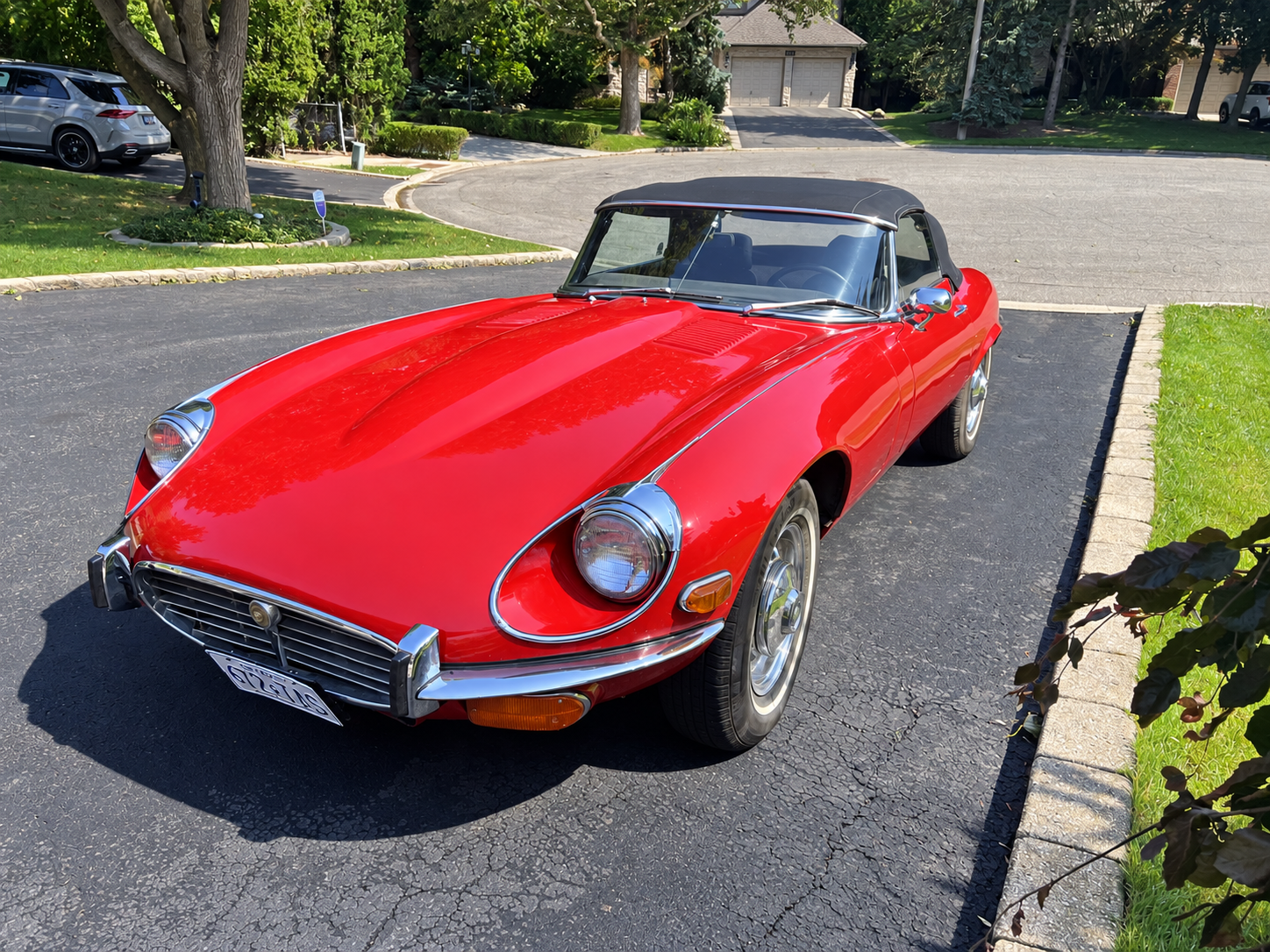 Sunlit Classic Red Convertible on a Suburban Driveway.png