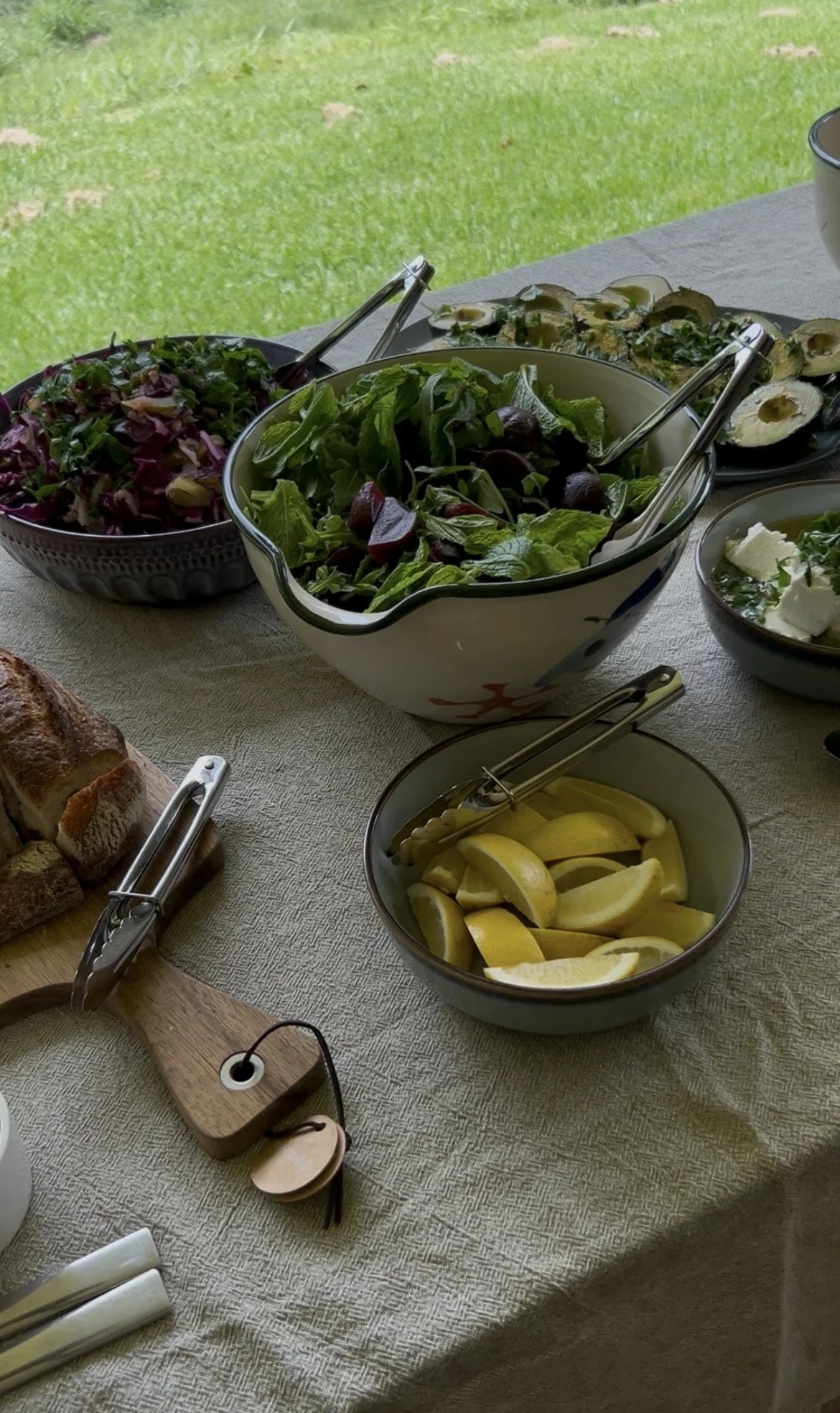 Salad with cherry tomatoes, lemon wedges, avocado halves, and other fresh vegetables on a dining table
