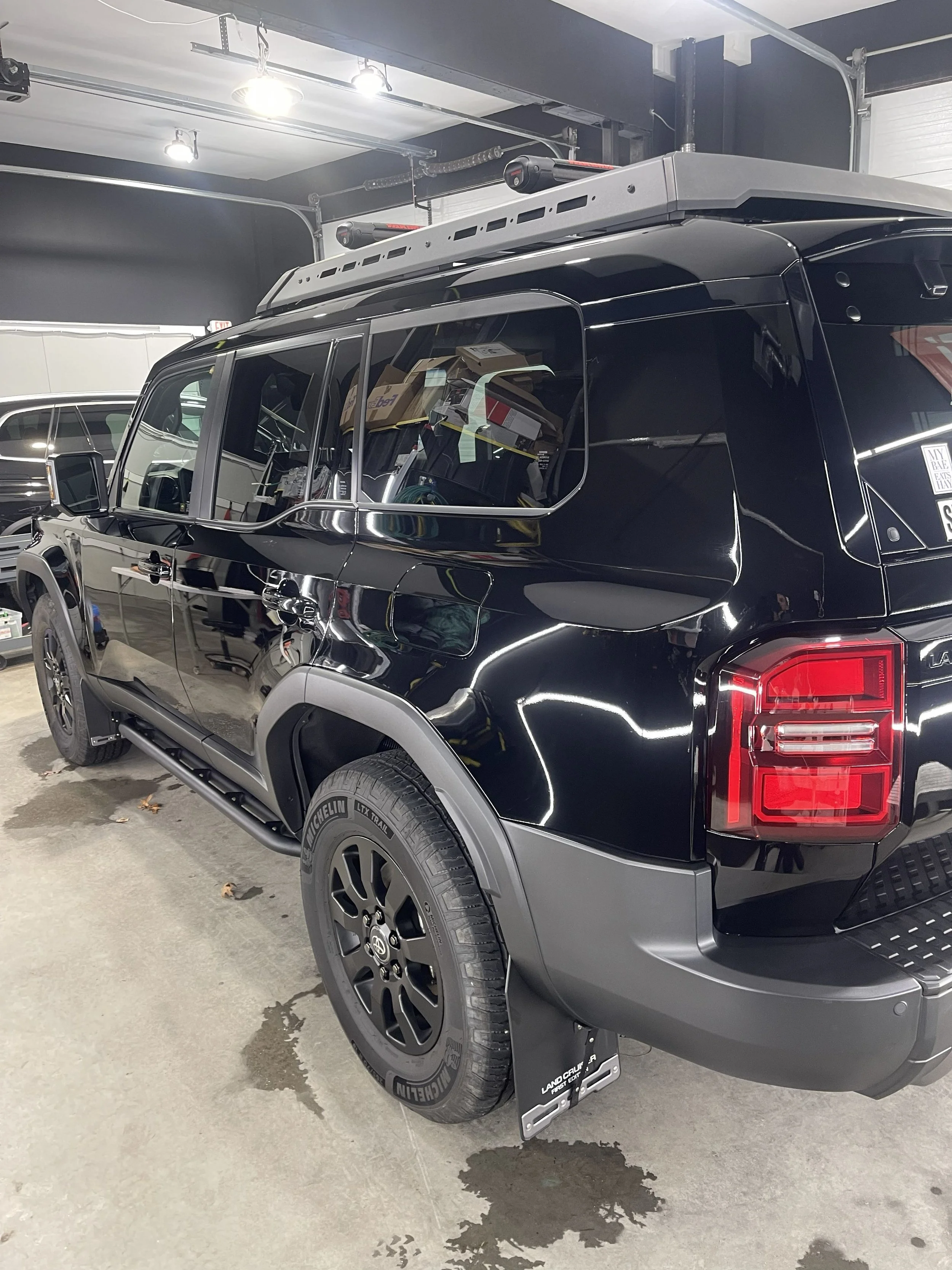 Black off-road vehicle with roof rack in a parking garage.