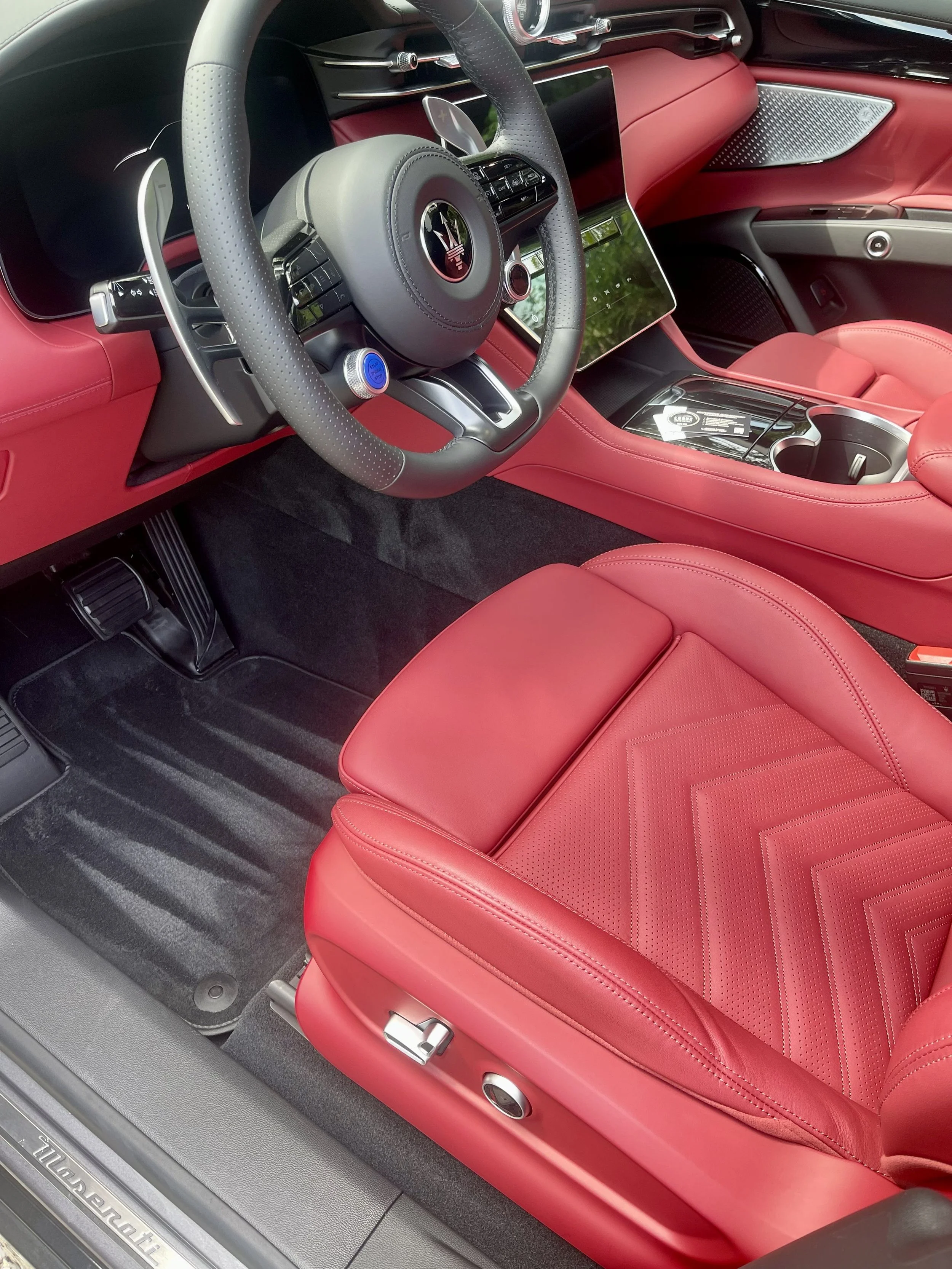 Interior of a luxury car with red leather seats, a sleek dashboard, and advanced controls, featuring Maserati branding.