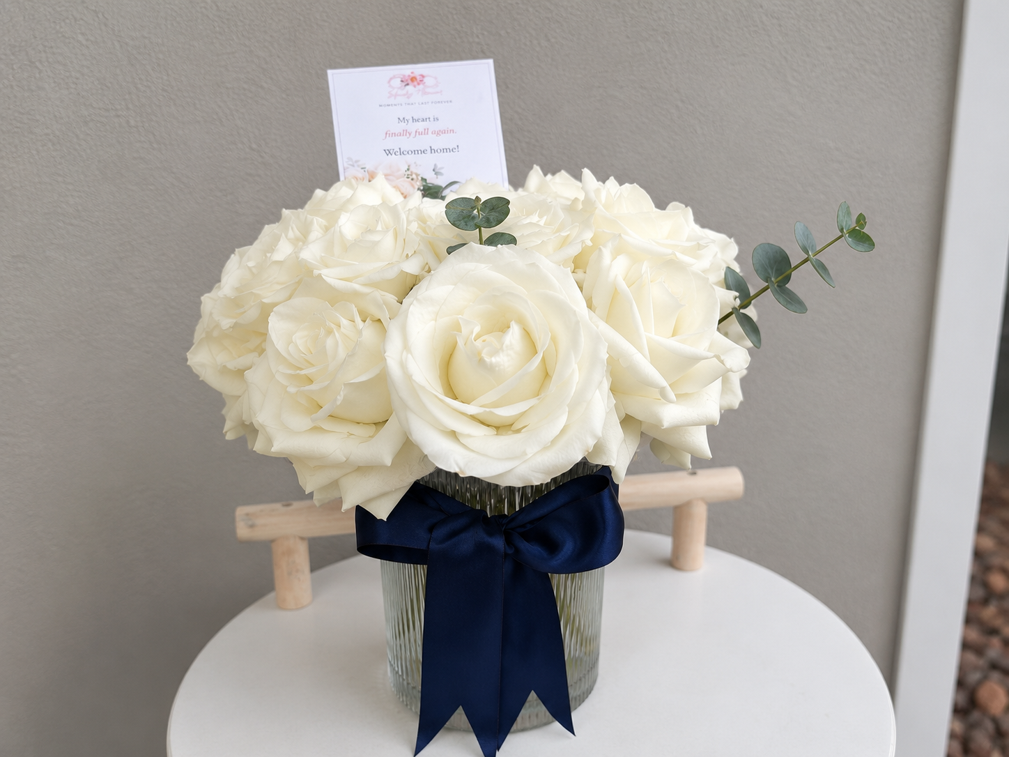 Classic White Rose Arrangement in a glass vase with eucalyptus and satin ribbon