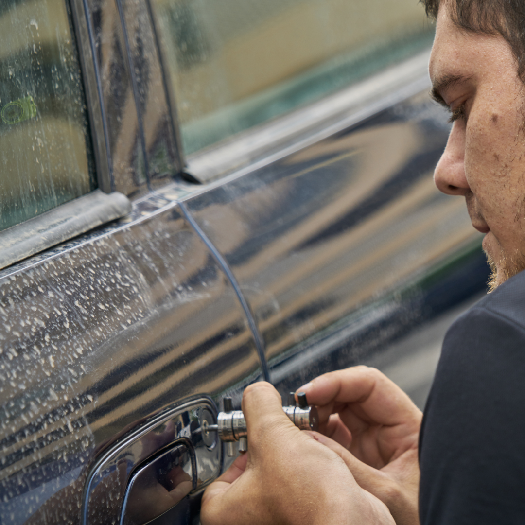 A man using a screwdriver to lock a car door.