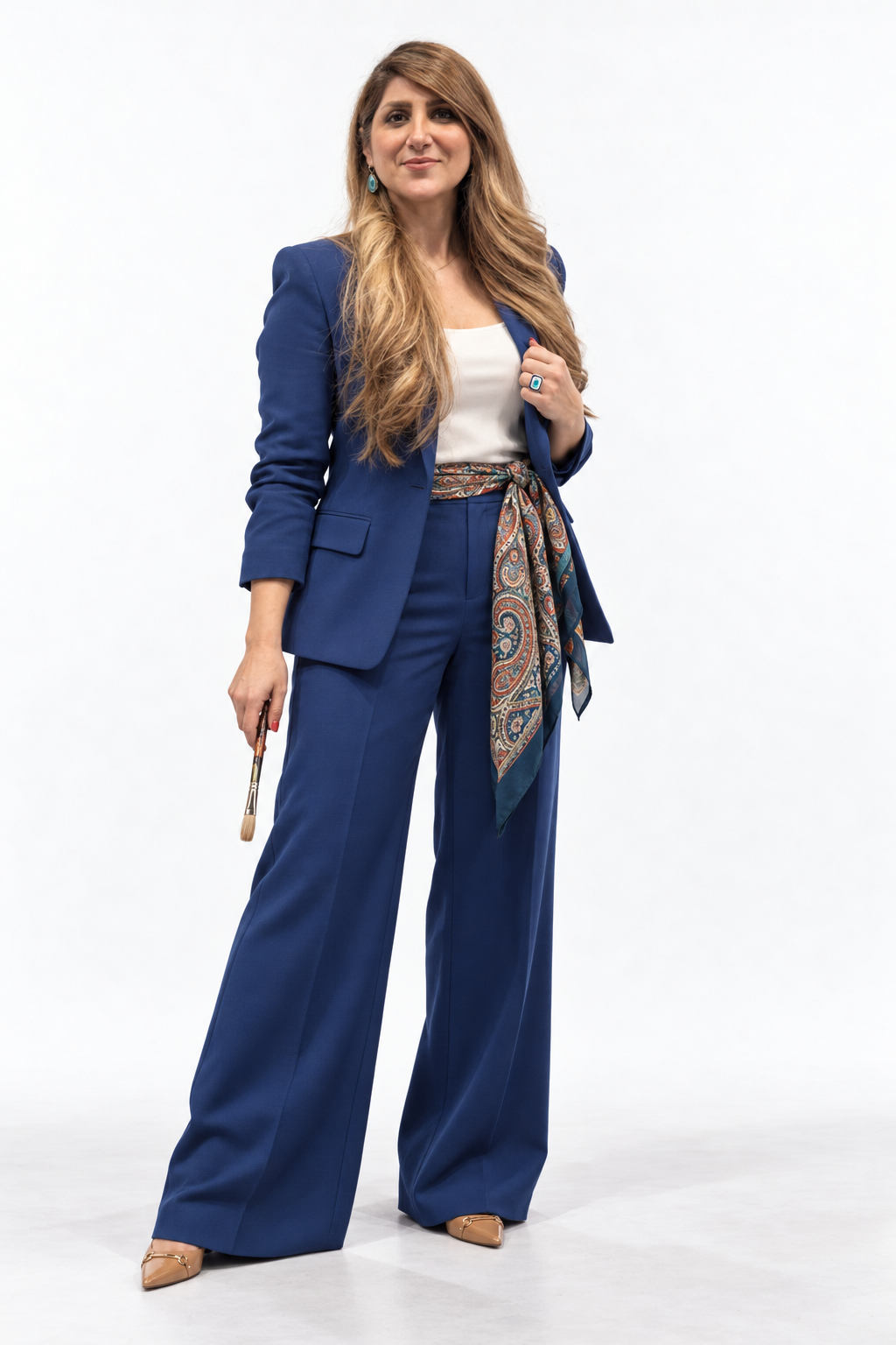 01 · Ultramarine Authority
A tailored ultramarine suit, patterned waist scarf, and turquoise accents on white seamless. Direct eye contact and a relaxed brush-holding pose communicate a confident artistic point of view. AI-generated shoot concept.