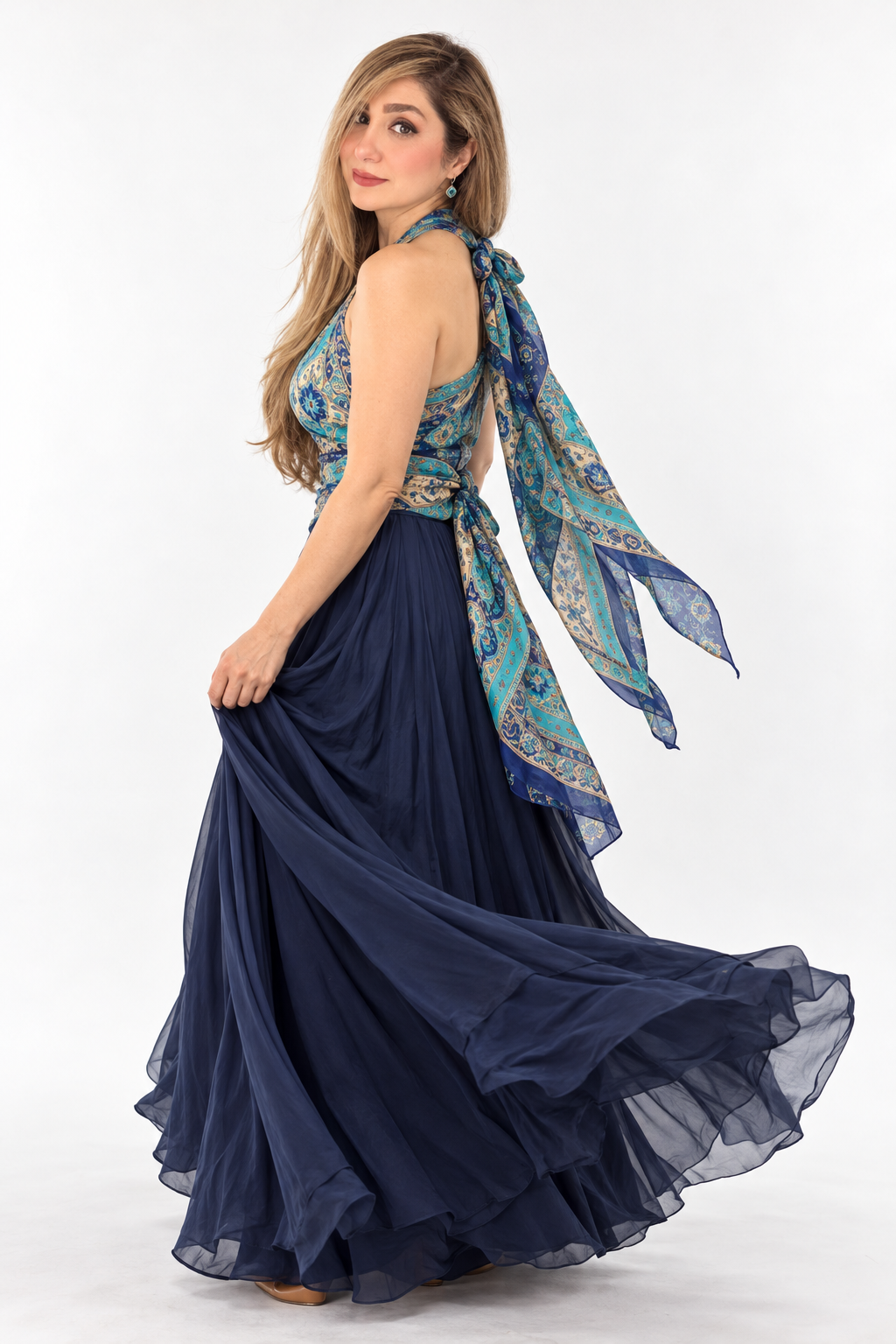 03 · Pattern in Motion
A turquoise paisley scarf top and sweeping navy skirt on white seamless. A gentle turn and over-the-shoulder gaze let the fabric move, expressing heritage through a contemporary, playful silhouette. AI-generated shoot concept.