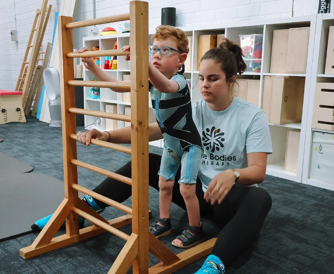 Child climbing therapy equipment with therapist support during a clinic session