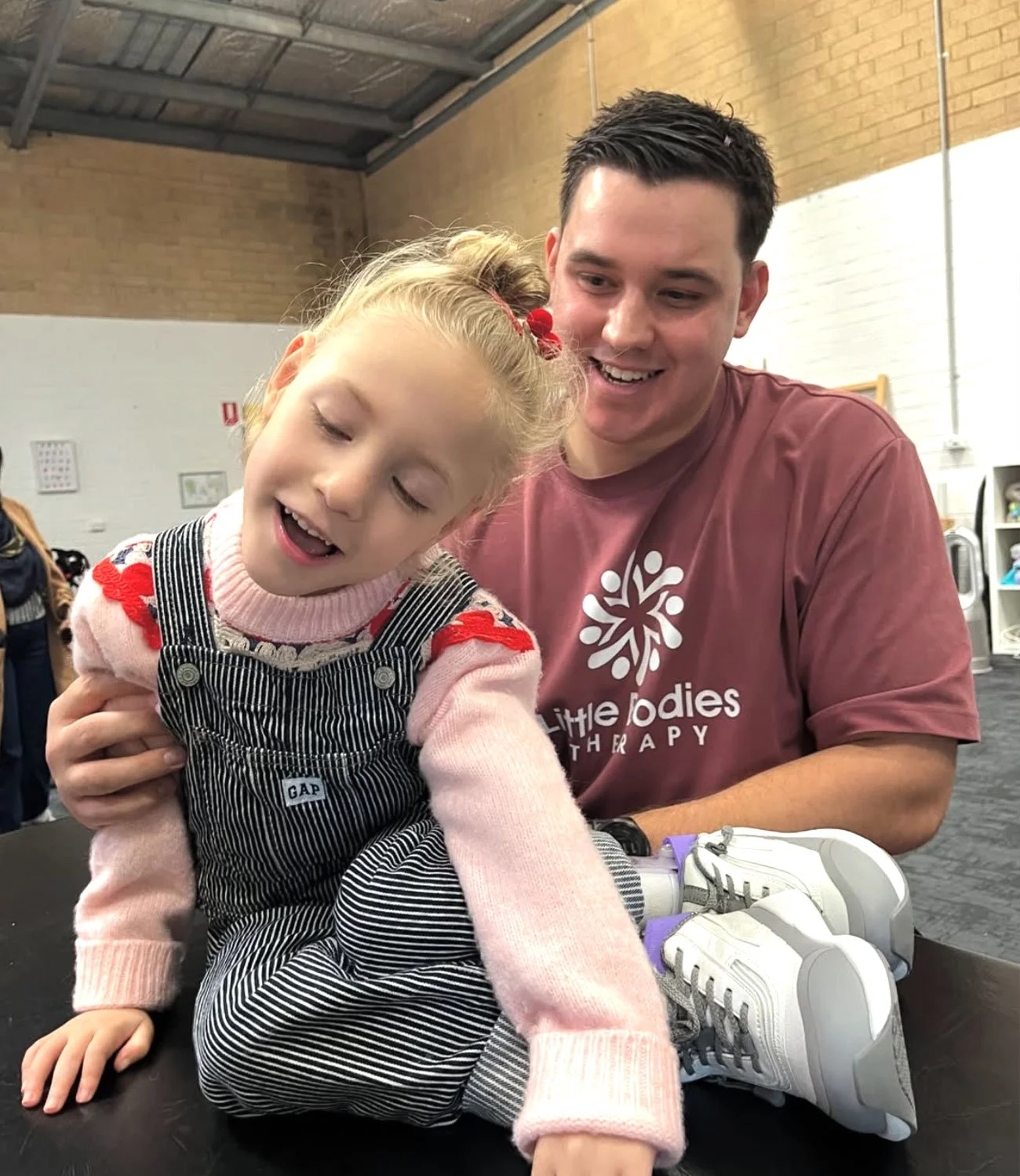 Therapist supports child in sitting upright