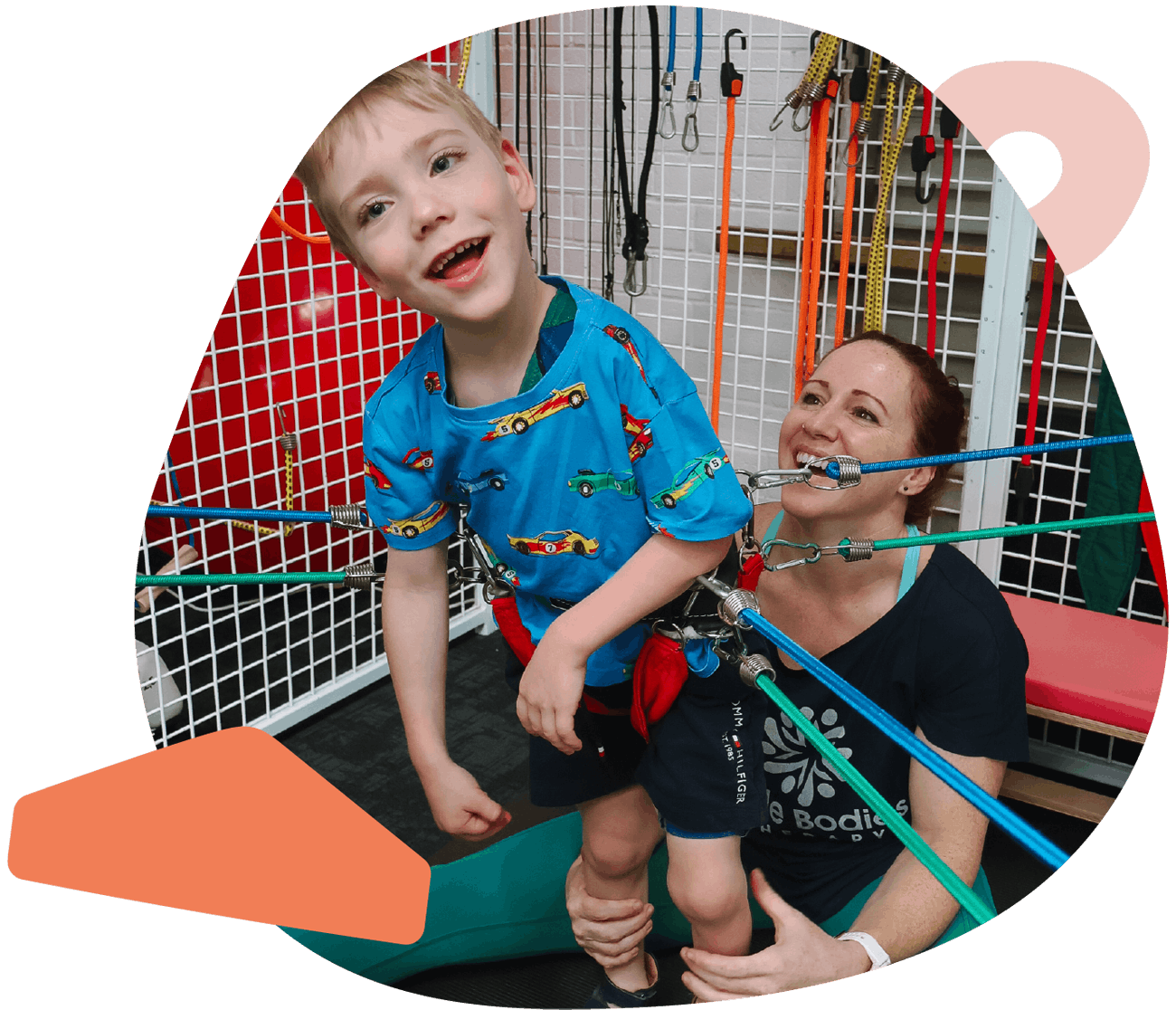 Child and therapist smiling in clinic during a physiotherapy therapy cage session