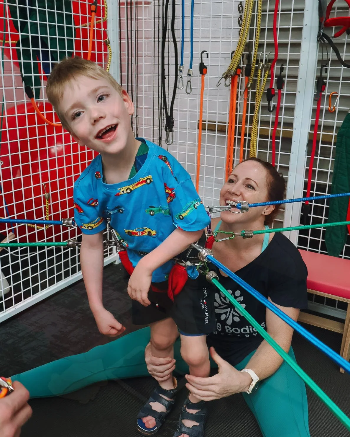 Child practising gross motor movement with therapist support during a clinic session