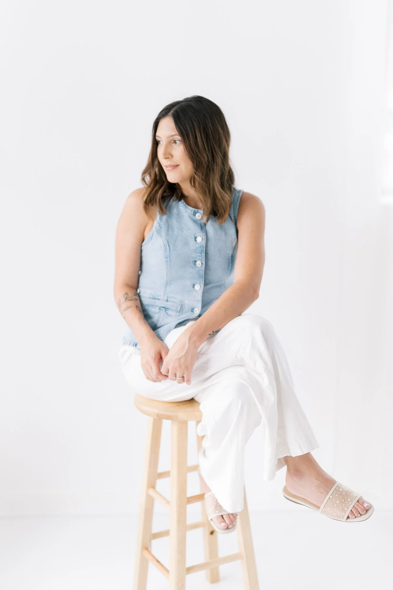 Tristan sitting on a stool in her studio, facing the window