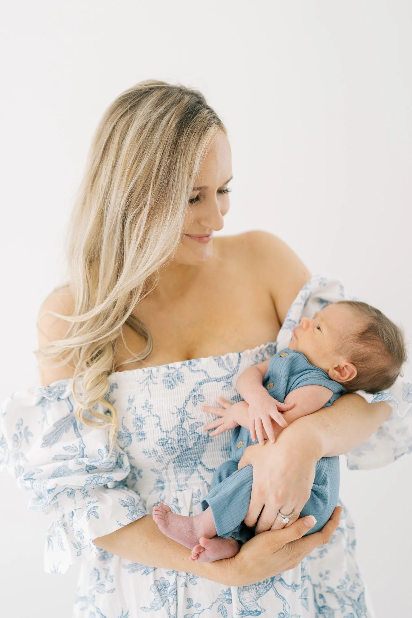 Mom in blue dress holding newborn son in studio