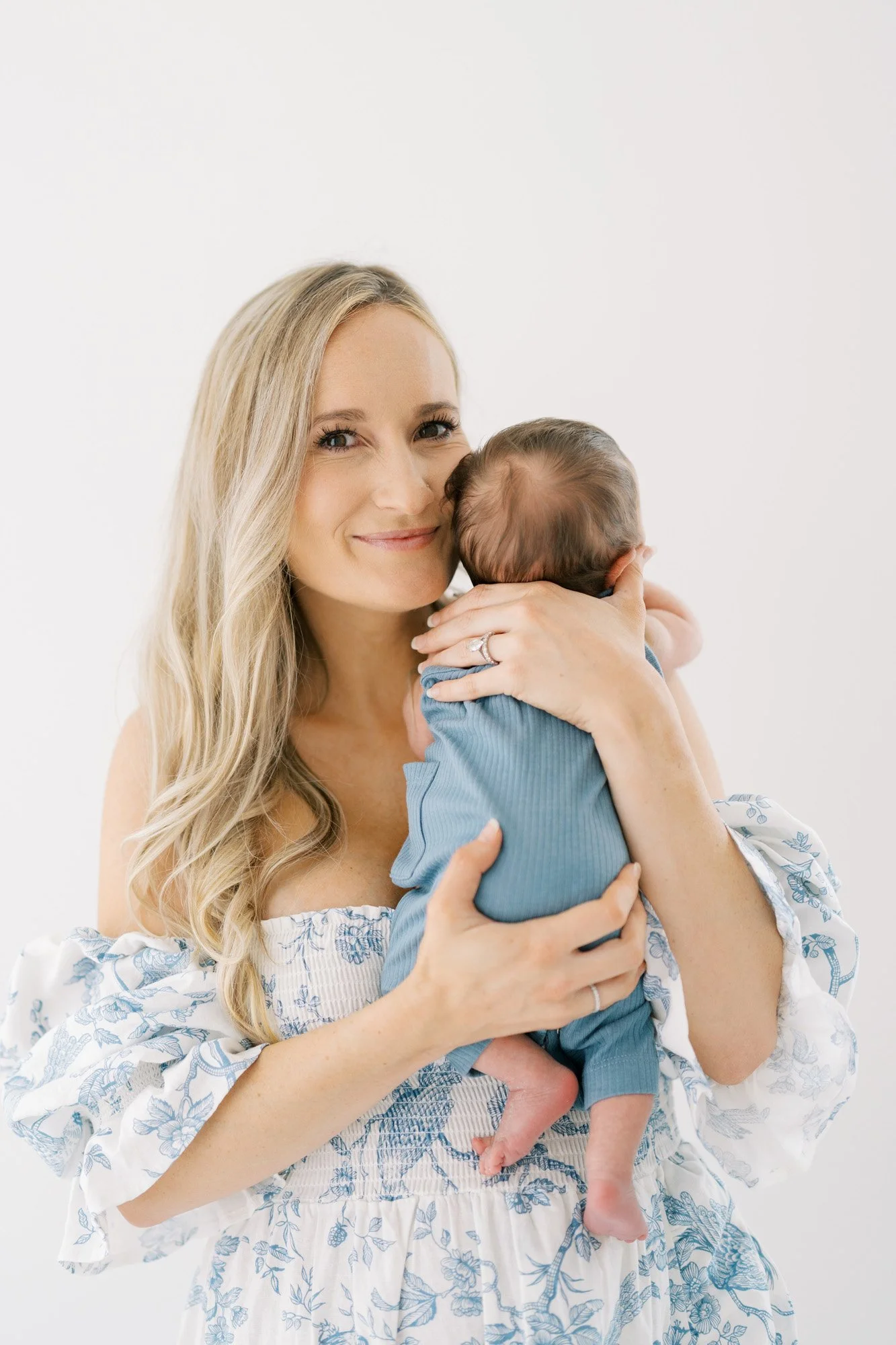 Mom holding newborn on shoulder smiling