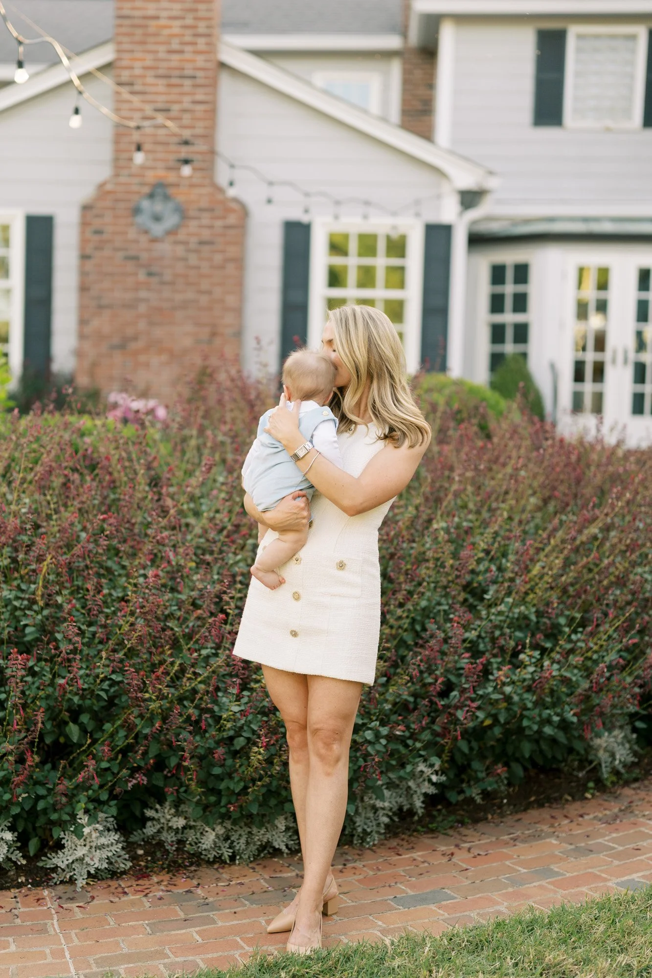 Mother holding her infant son in front of a beautiful home in st. louis