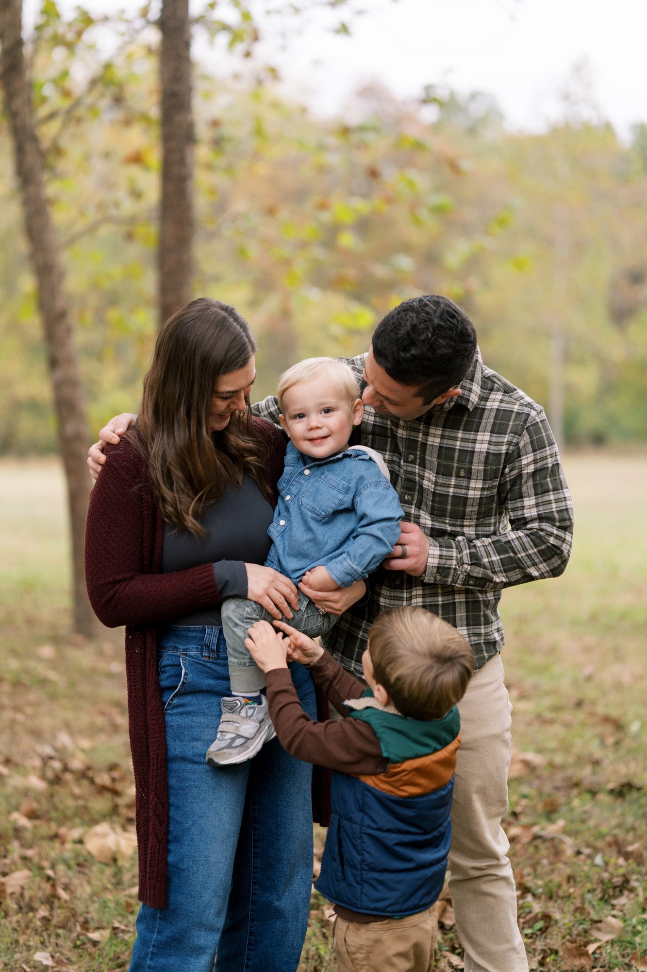 Mom and dad looking at toddler son smiling at camera in Wildwood Community Park