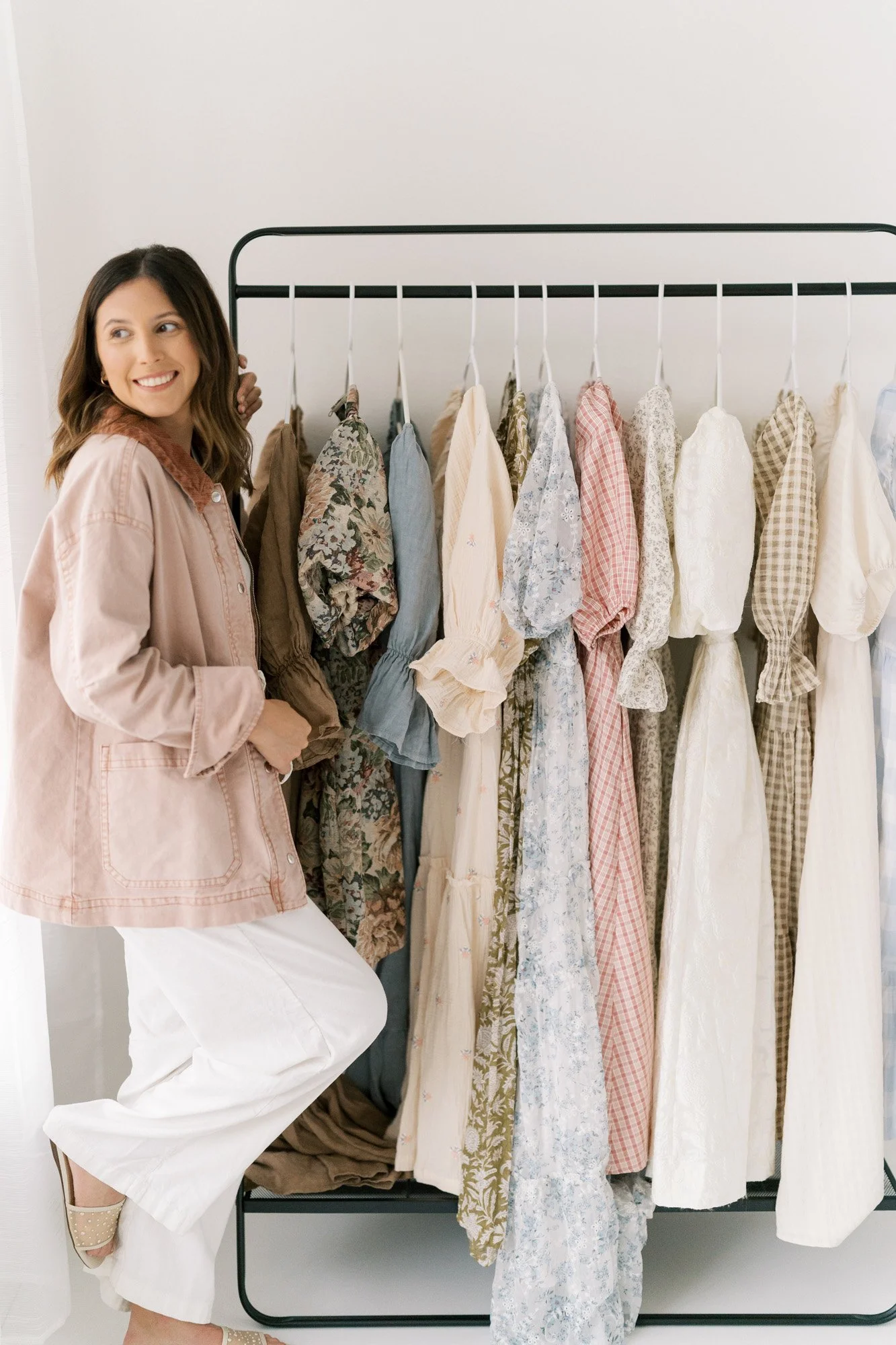 Tristan standing in front of clothes rack with maternity dresses from client wardrobe