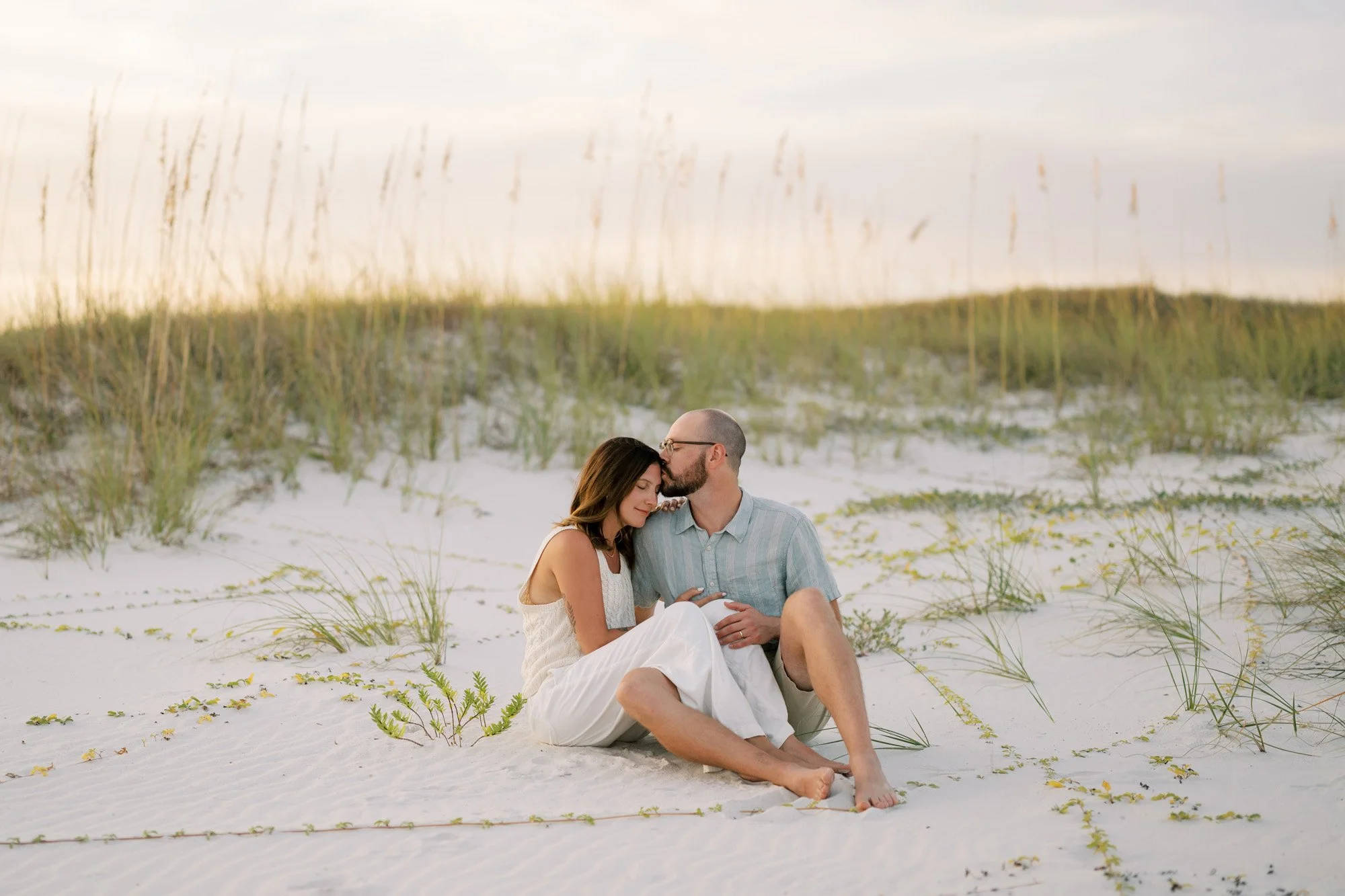Tristan and her husband sitting in the sand at sunset