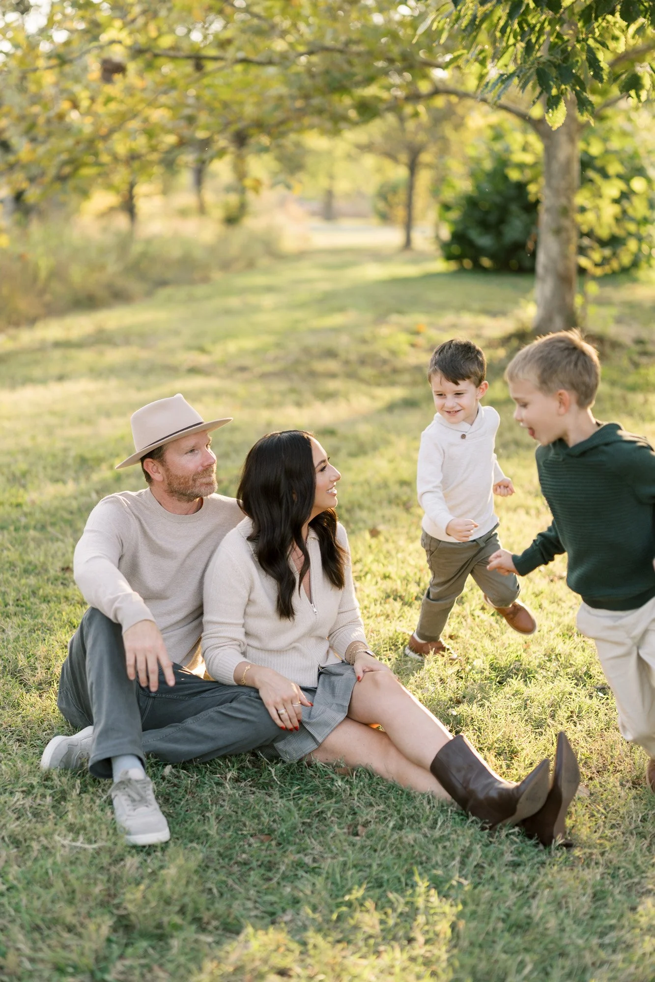 Parents sitting on grass with boys running around them during photo session