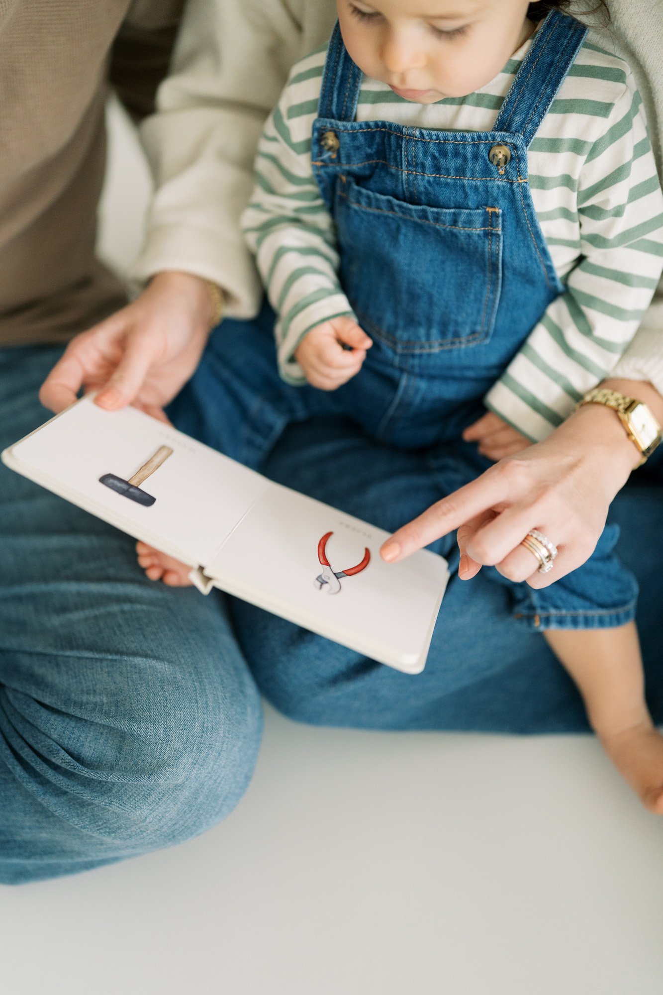 Mom and toddler son sitting on the studio floor looking at a picture book