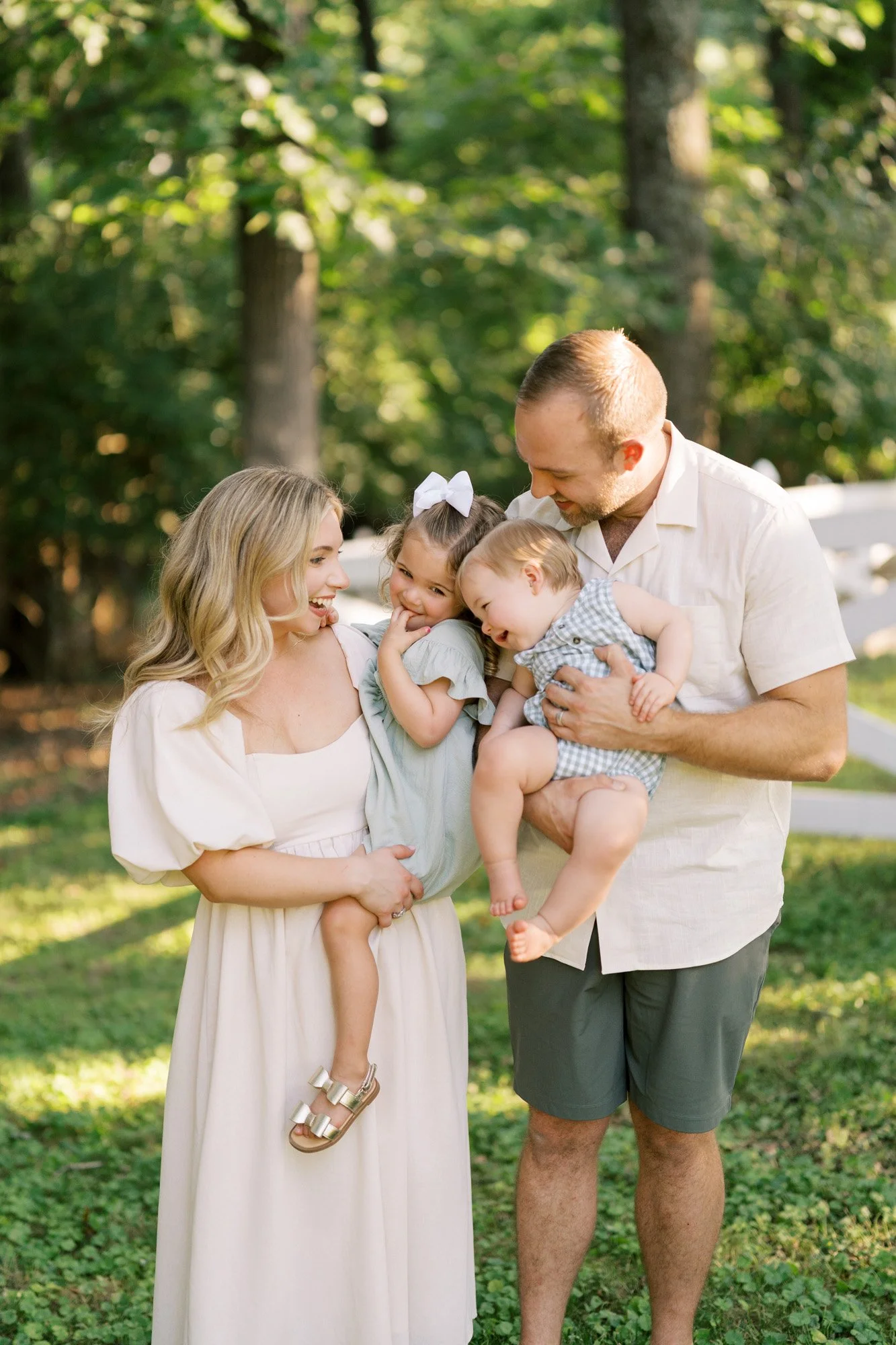 Mom and Dad standing holding two girls between them outdoors