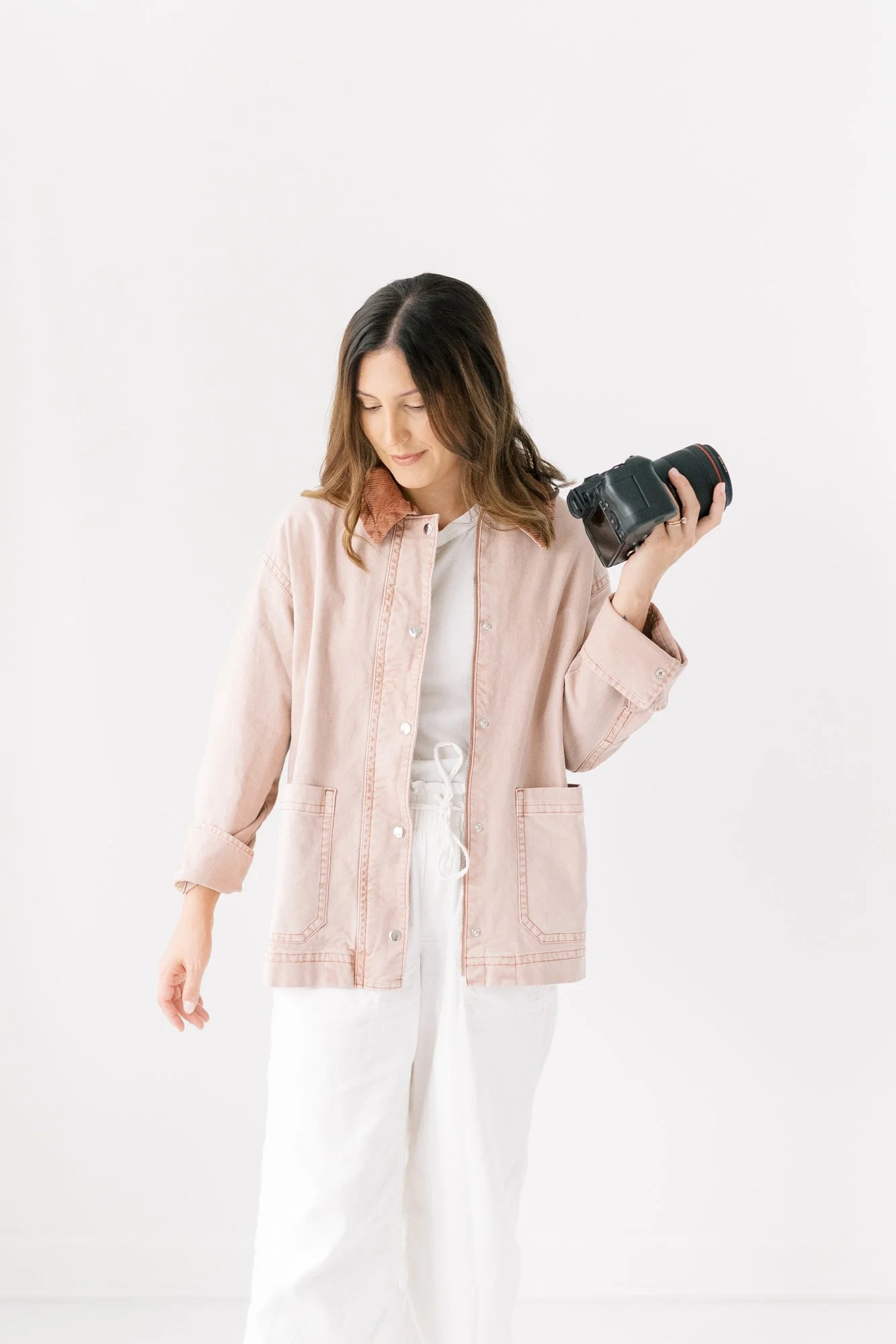 Tristan in light pink canvas jacket in studio holding camera