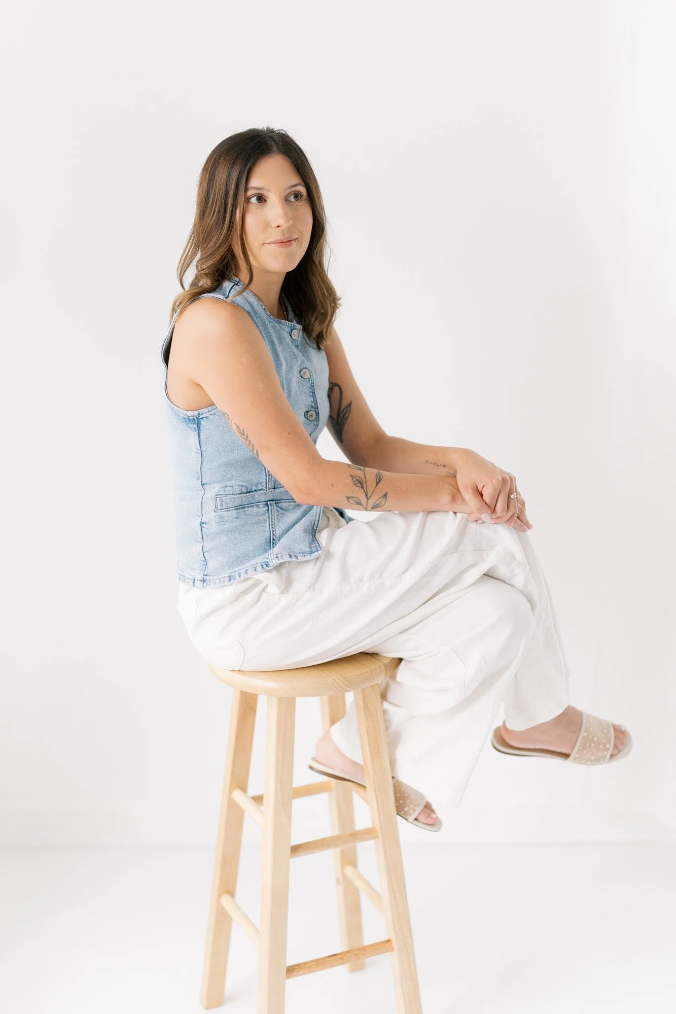 Tristan sitting on a stool in her studio, legs crossed and smiling across the room