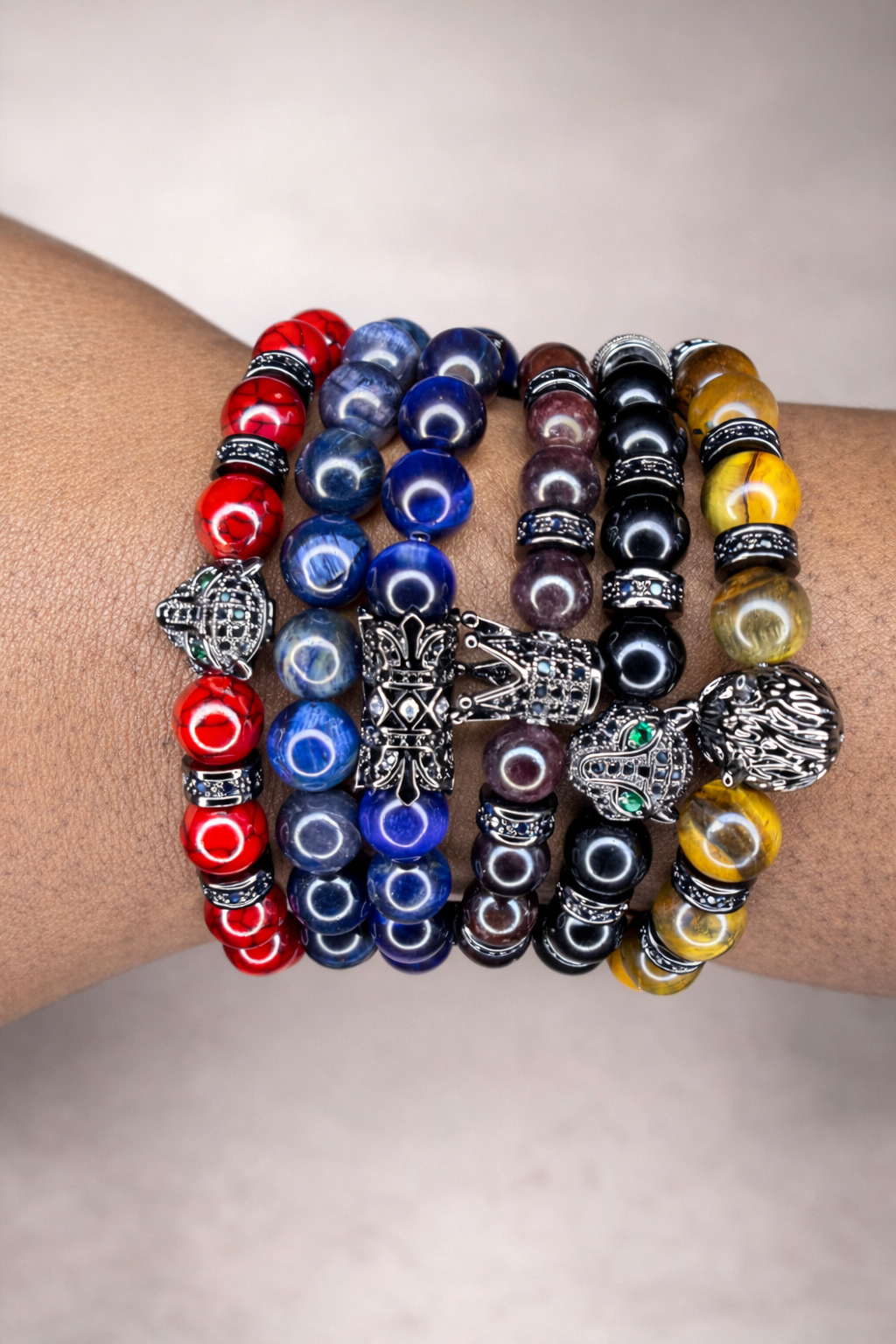 Multiple colorful beaded bracelets with silver charms on a wrist.