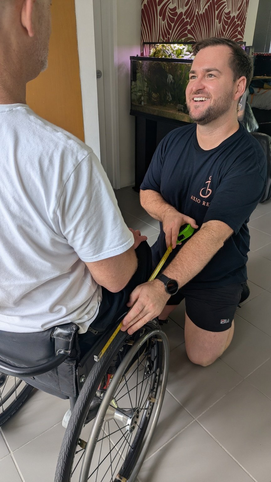 Specialist neurological physiotherapist taking measurements for a customized wheelchair prescription as part of an NDIS equipment assessment.