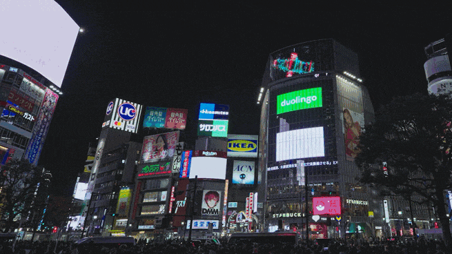 Brightly lit cityscape at night with digital billboards and skyscrapers.