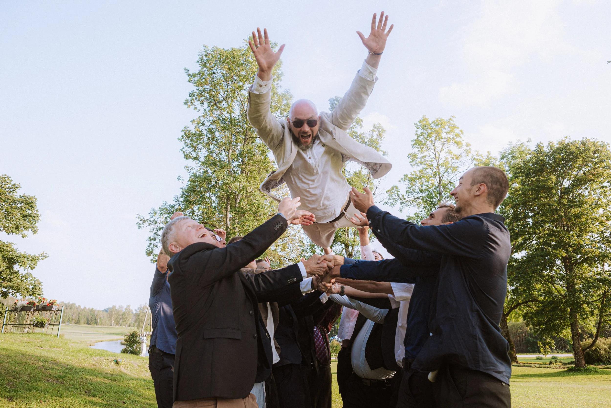Līgavainis pacelts gaisā priecīgā kāzu svinību mirklī.