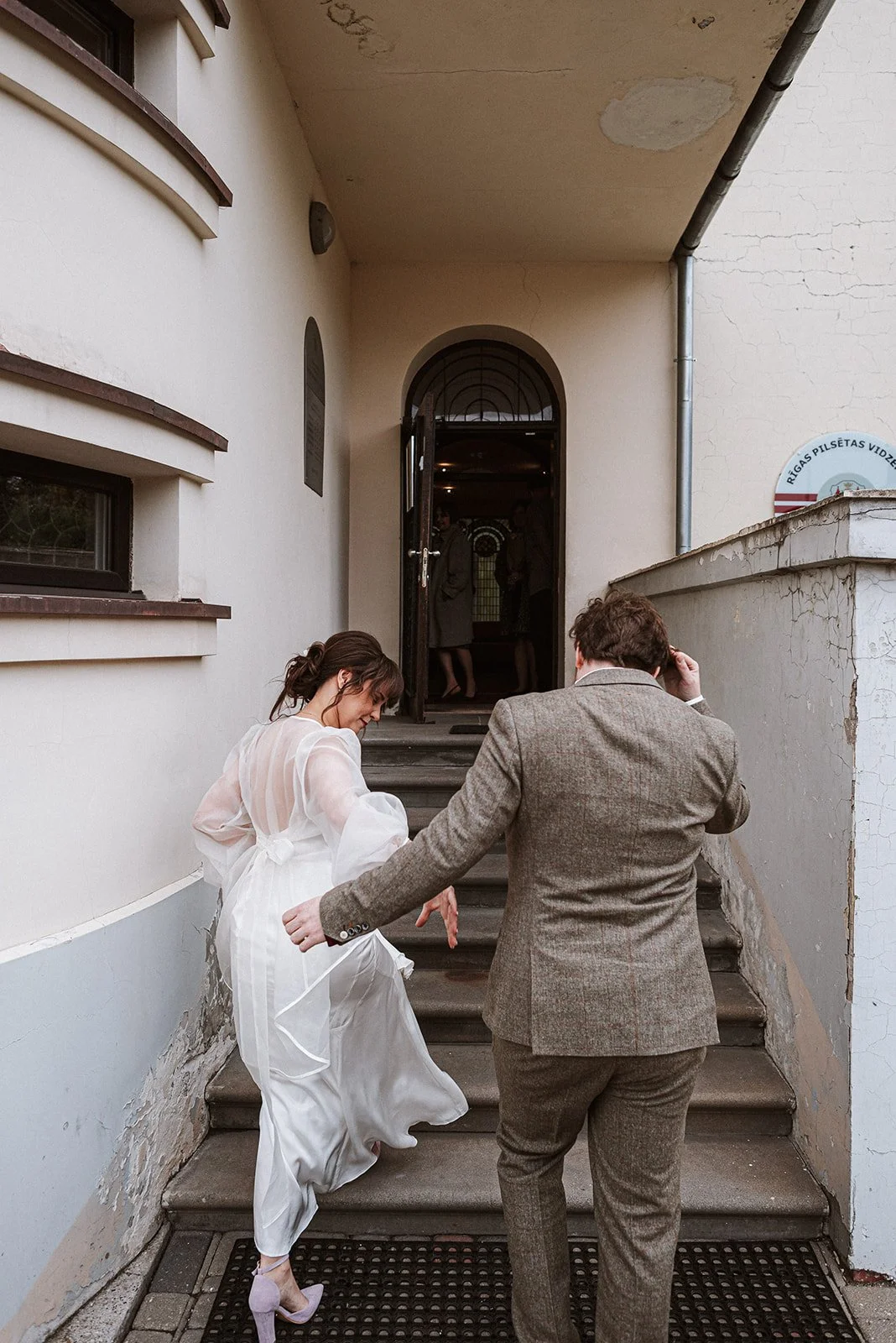 Kāzu pāris iznāk no ceremonijas ēkas.