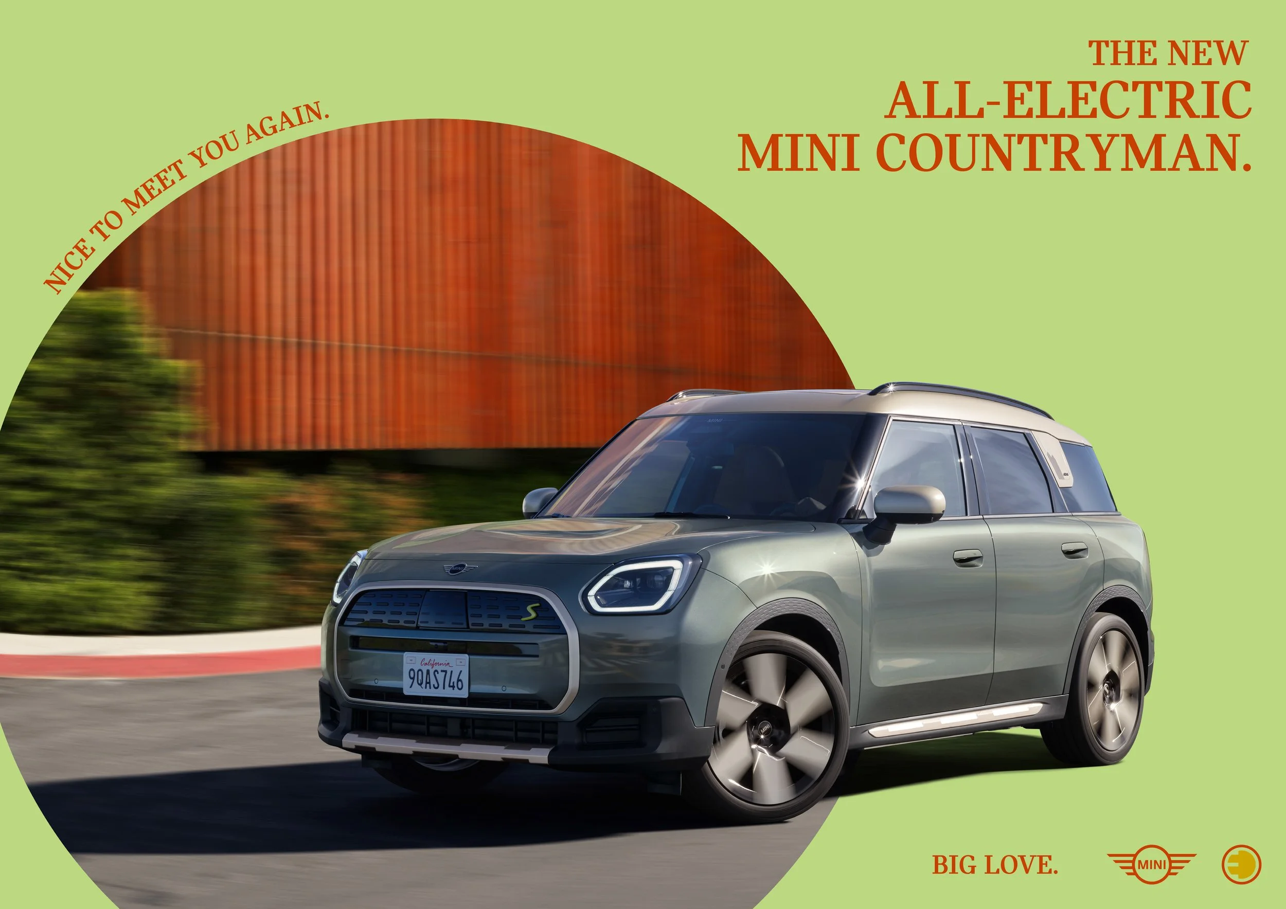 Ein grüner MINI All-Electric Mini Countryman fährt auf einer Straße, mit einem orangefarbenen Gebäude im Hintergrund, und dem Text 'The new all-electric Mini Countryman' sowie Markenlogos und Hashtags.