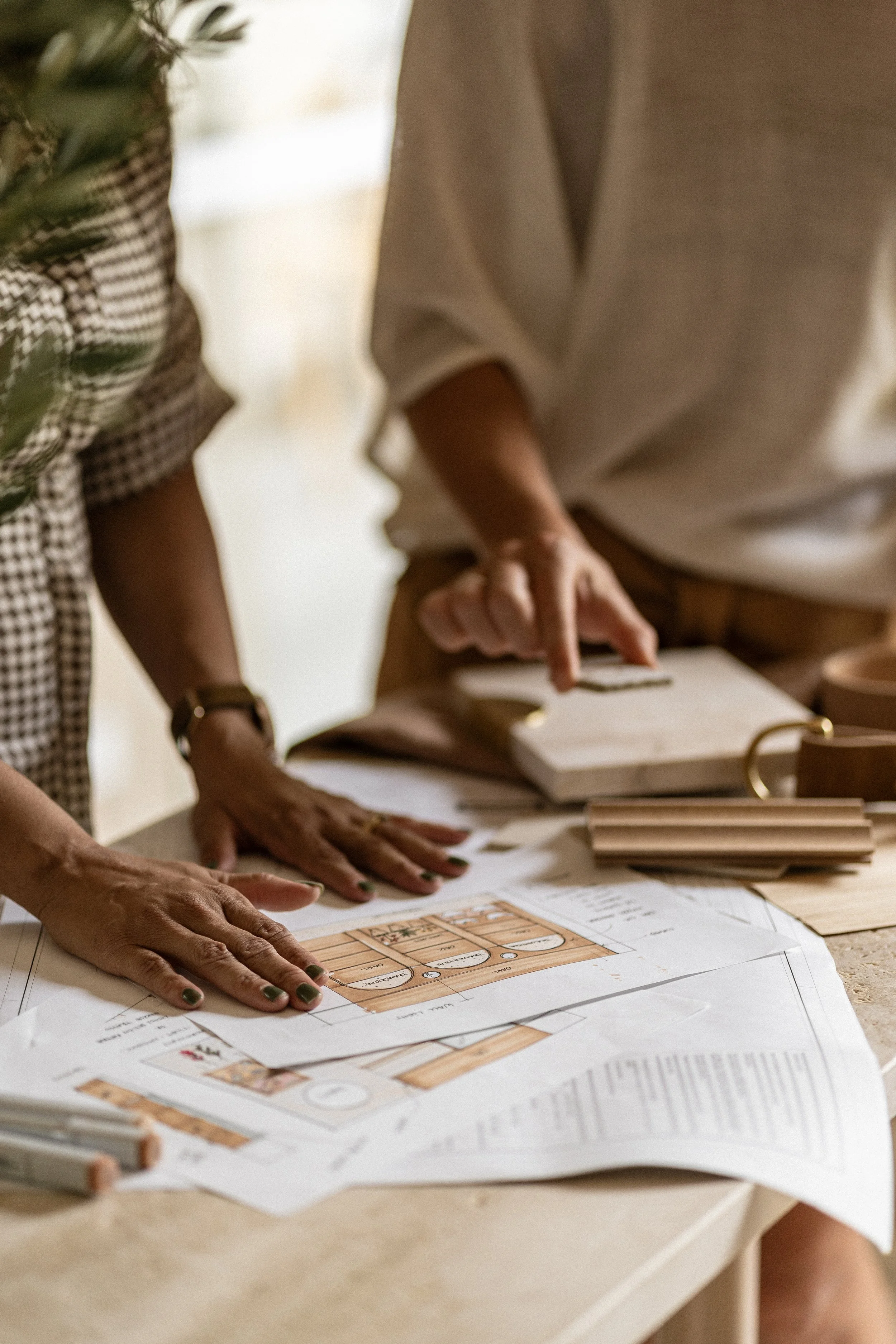 Two people reviewing architectural or interior design blueprints and material samples on a table.