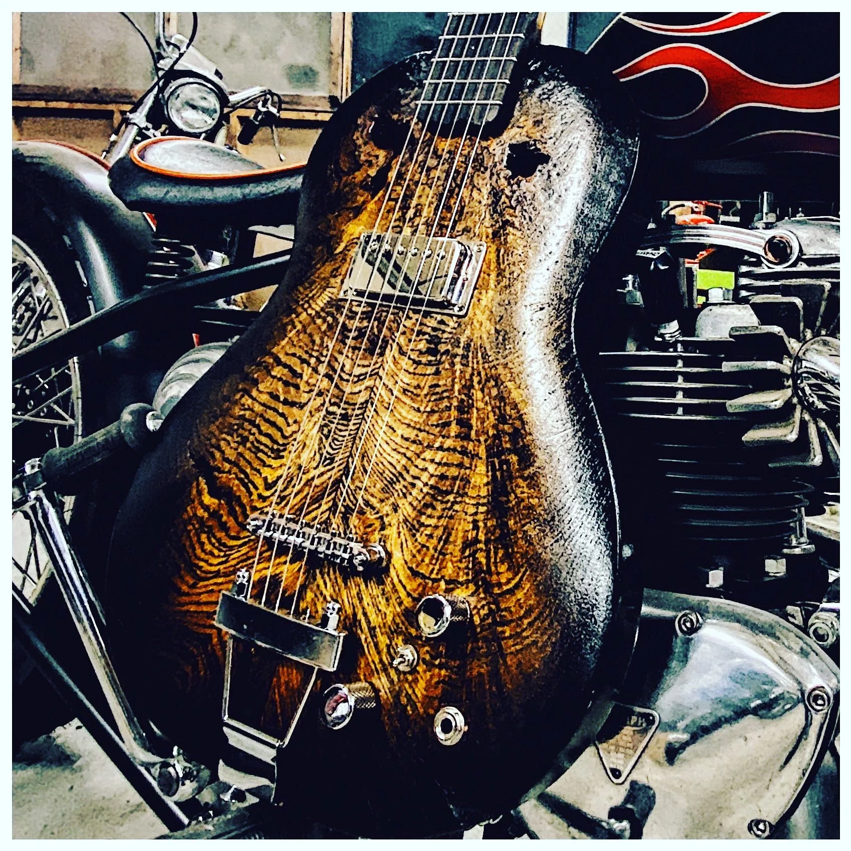 Close-up of a custom motorcycle with a wooden-textured guitar and black accents, parked indoors.
