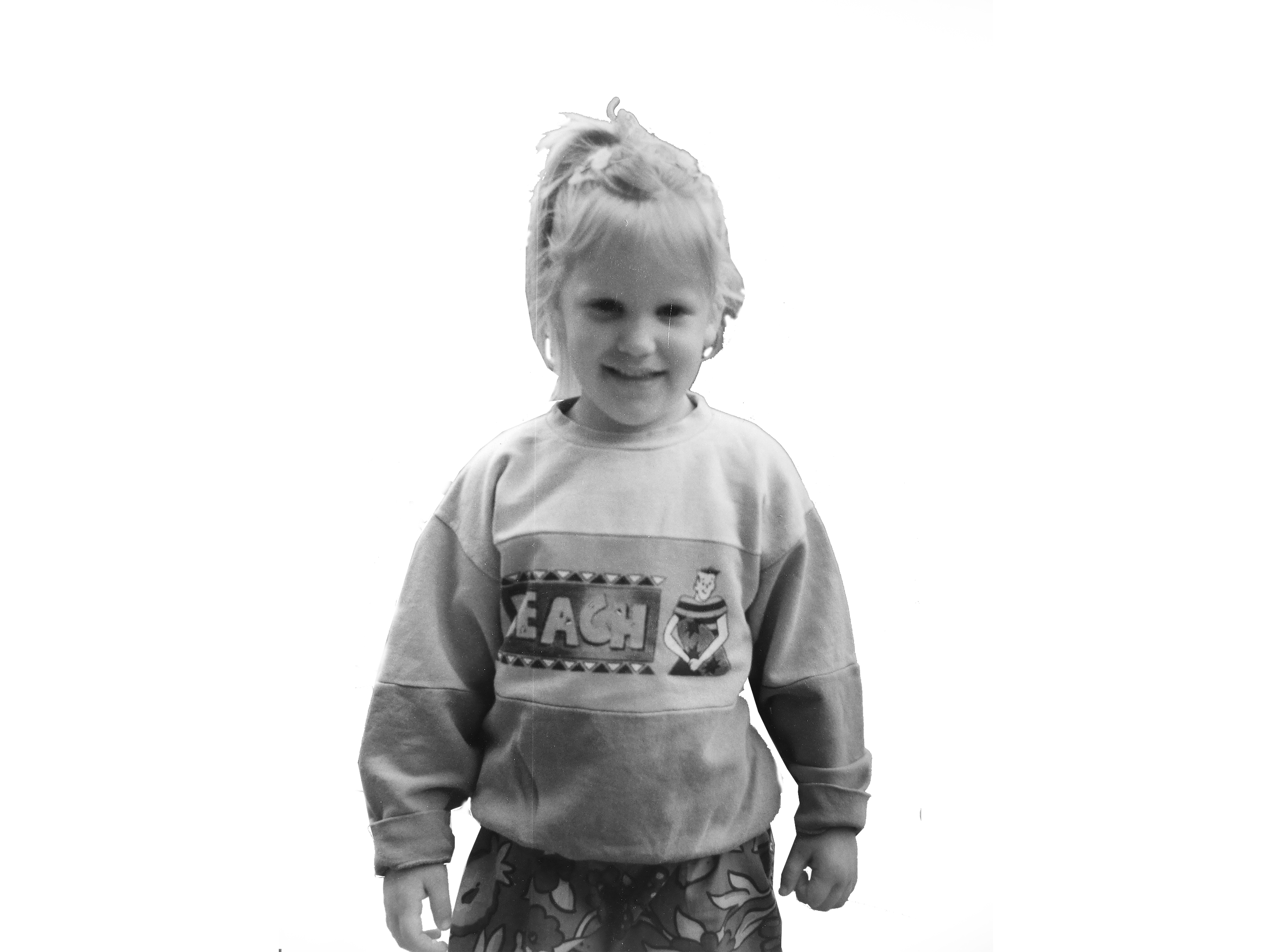 Ein kleines Mädchen mit blonden Haaren, das ein Sweatshirt trägt und lächelt.