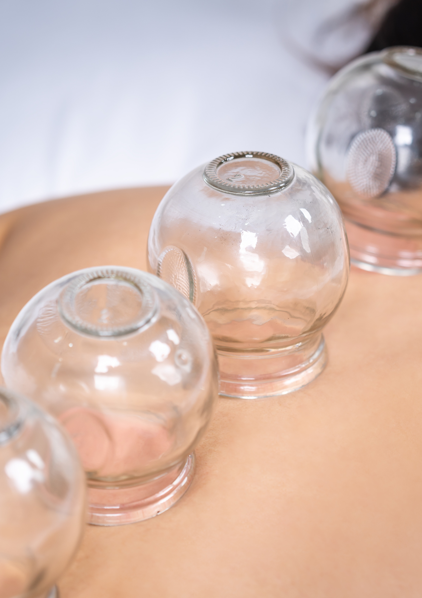 Close-up of upside-down glass jars with metal lids on a wooden surface with a blurred background.