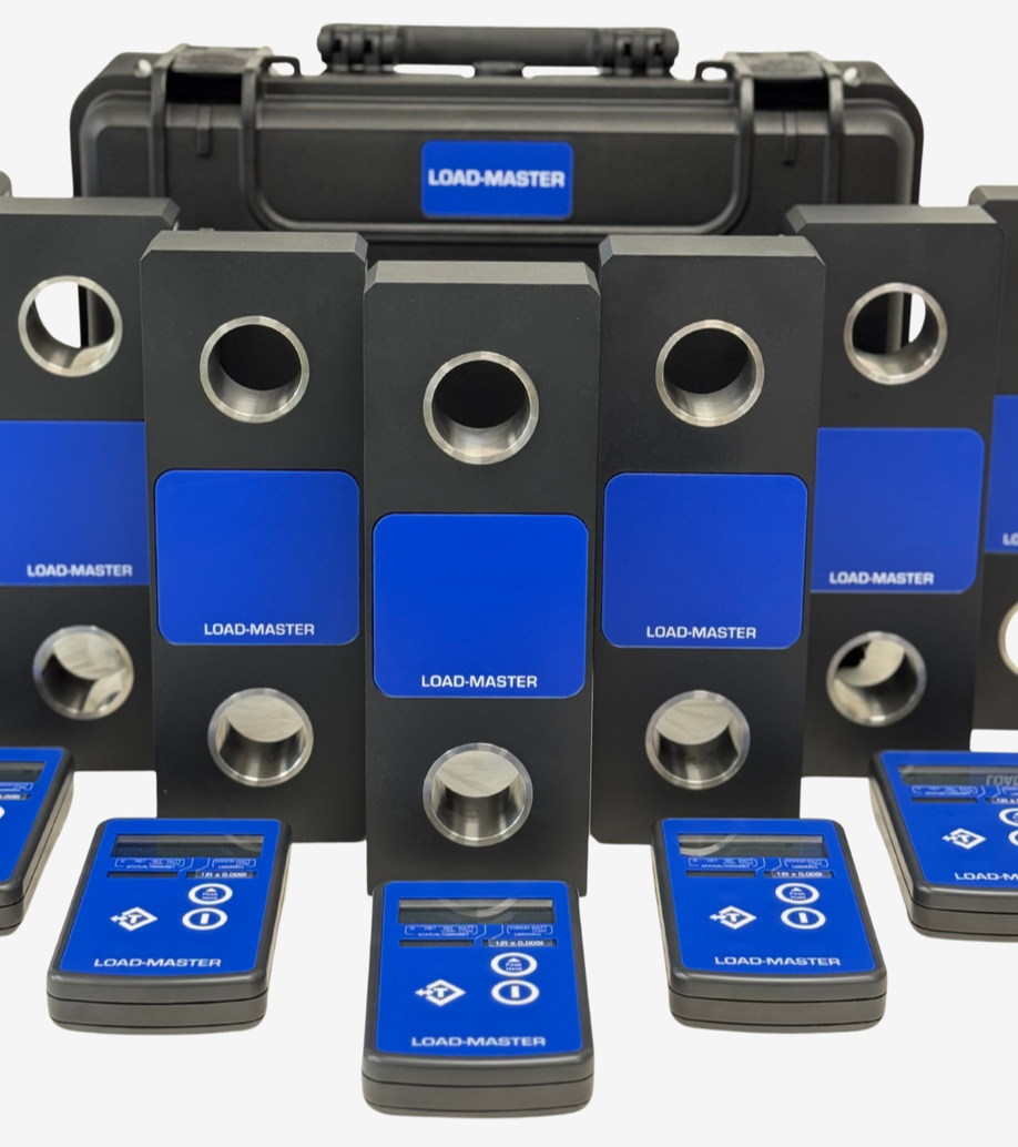 A collection of Load-Master hydraulic equipment, including multiple blue and black hydraulic control units and a black carrying case labeled 'LOAD-MASTER'.