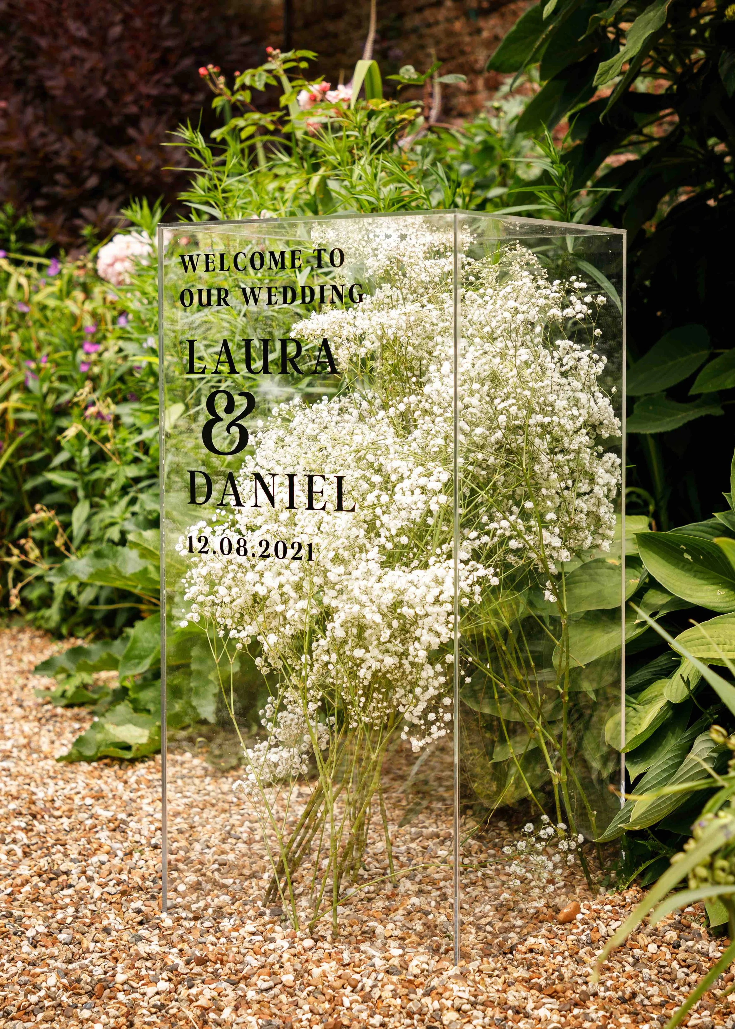 Luxury acrylic wedding welcome sign styled with delicate florals and modern typography for an elegant outdoor wedding.