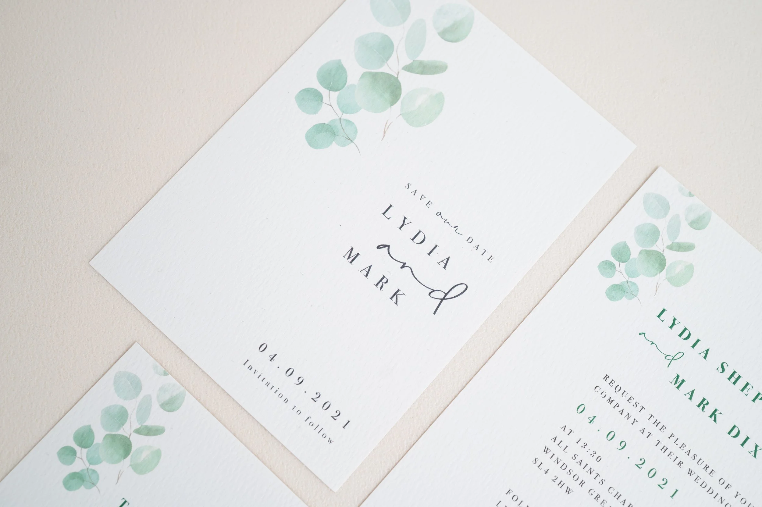Set of elegant save-the-date wedding invitations with green watercolor eucalyptus design, including details for Lydia and Mark's wedding on April 9, 2021.