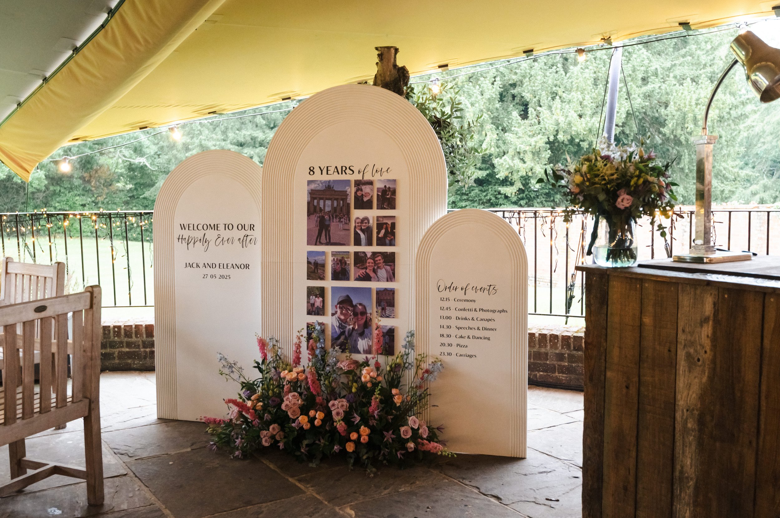Statement wedding signage installation featuring personalised story boards, photographs and floral arrangements tailored to the couple's journey.