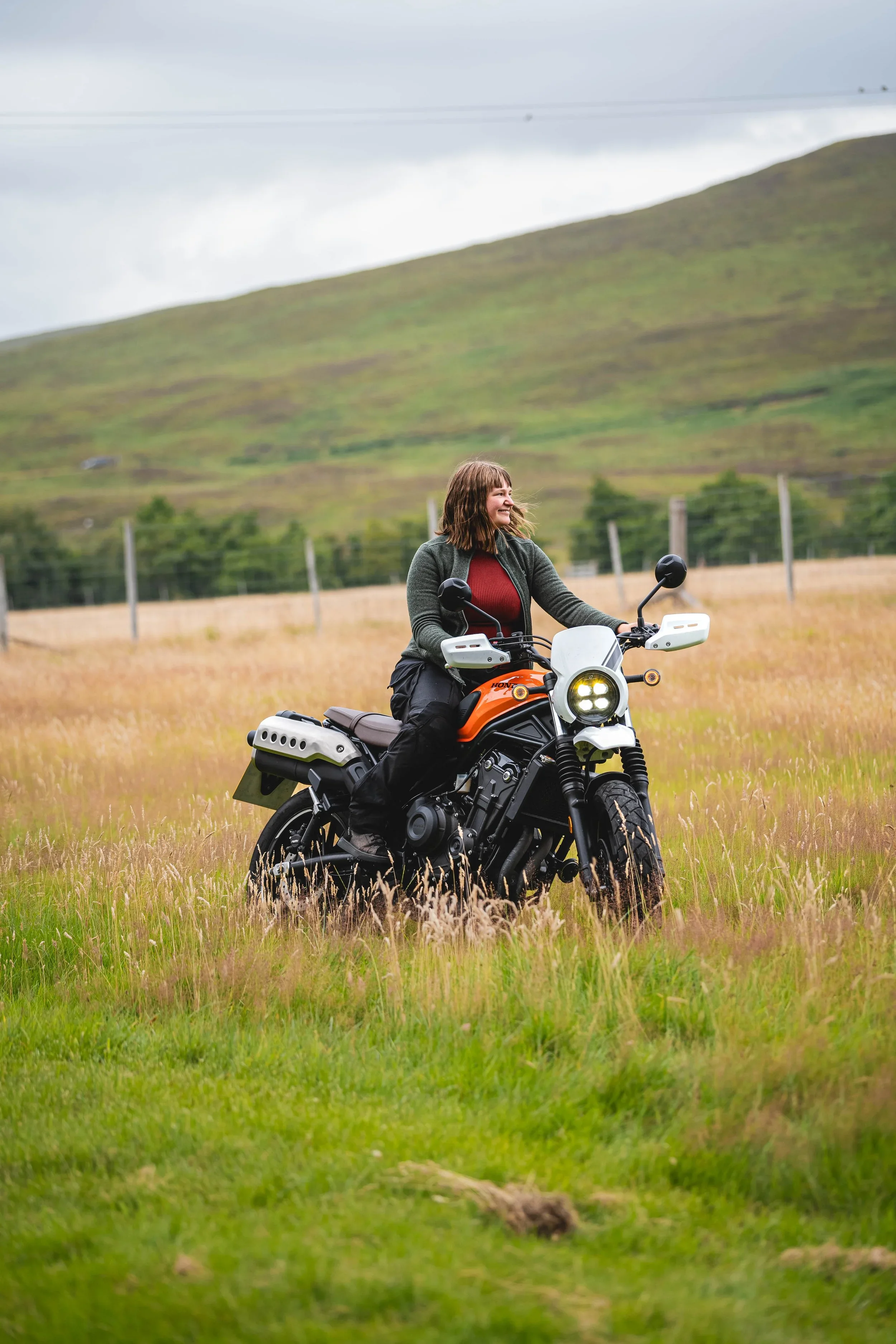 Girl on orange scrambler motorcycle in nature