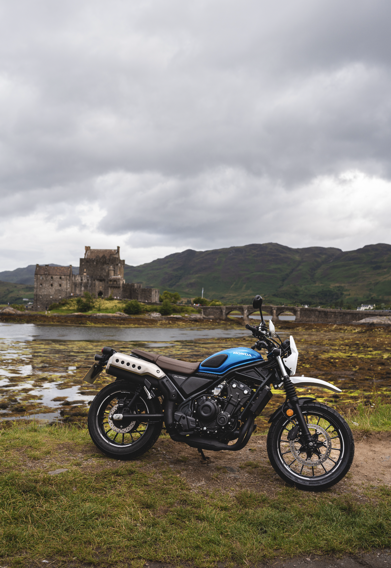 Blue scrambler motorcycle in front of castle