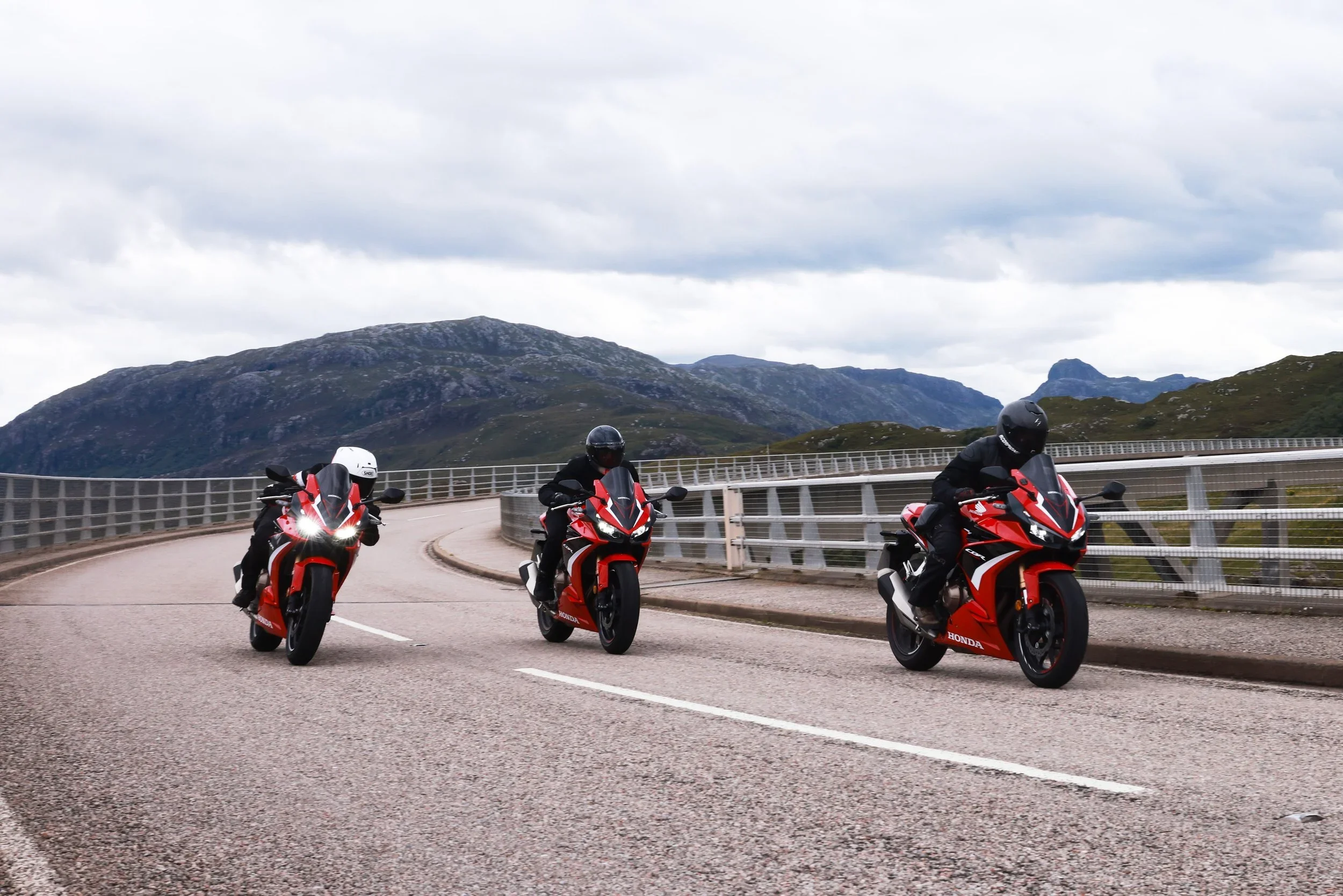 multiple supersport bikes riding across a bridge together