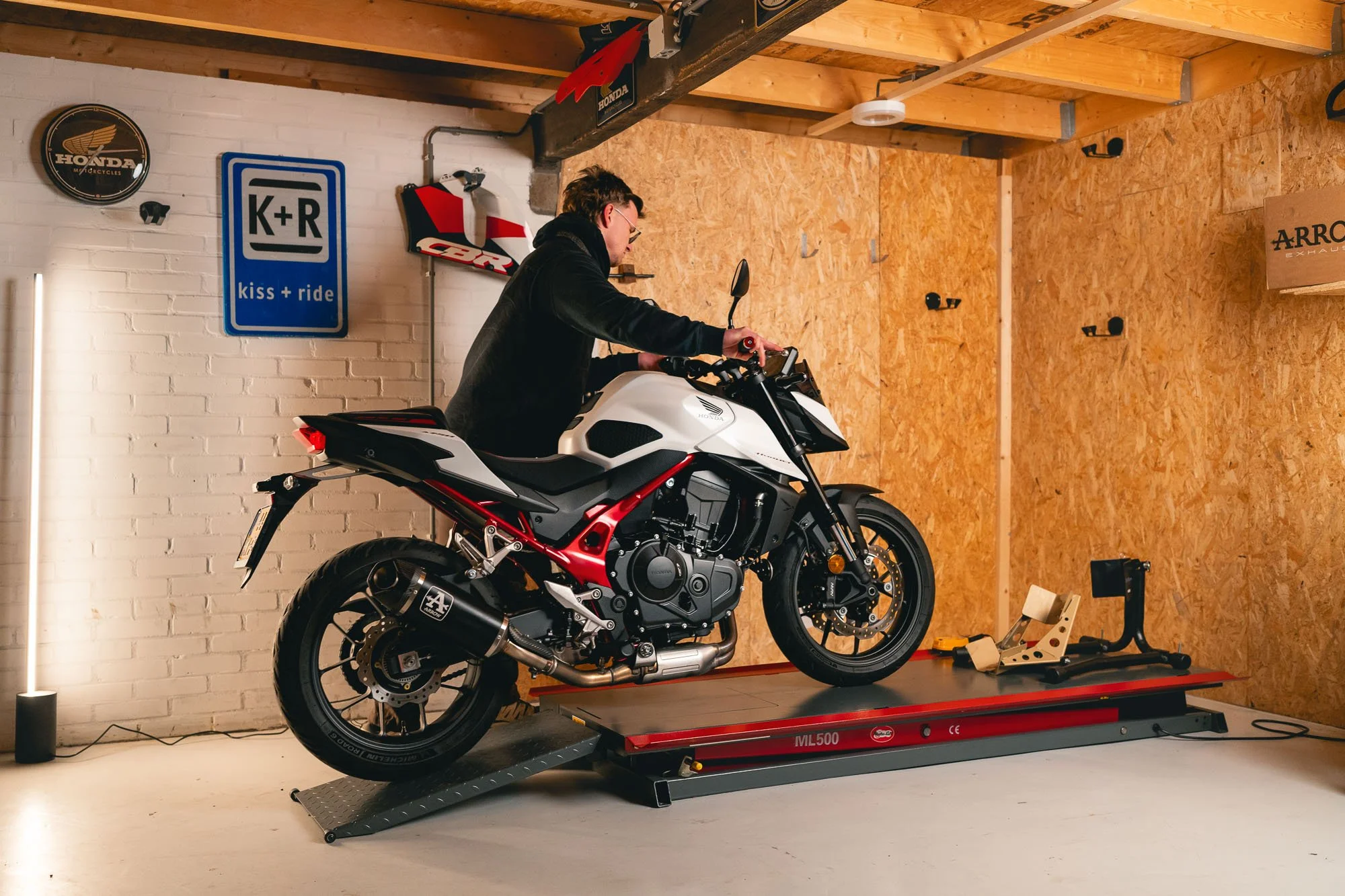 Jongeman duwd zijn naked bike, Honda Hornet 750 op een motorheftafel ML500 van Motorlijn Holland.