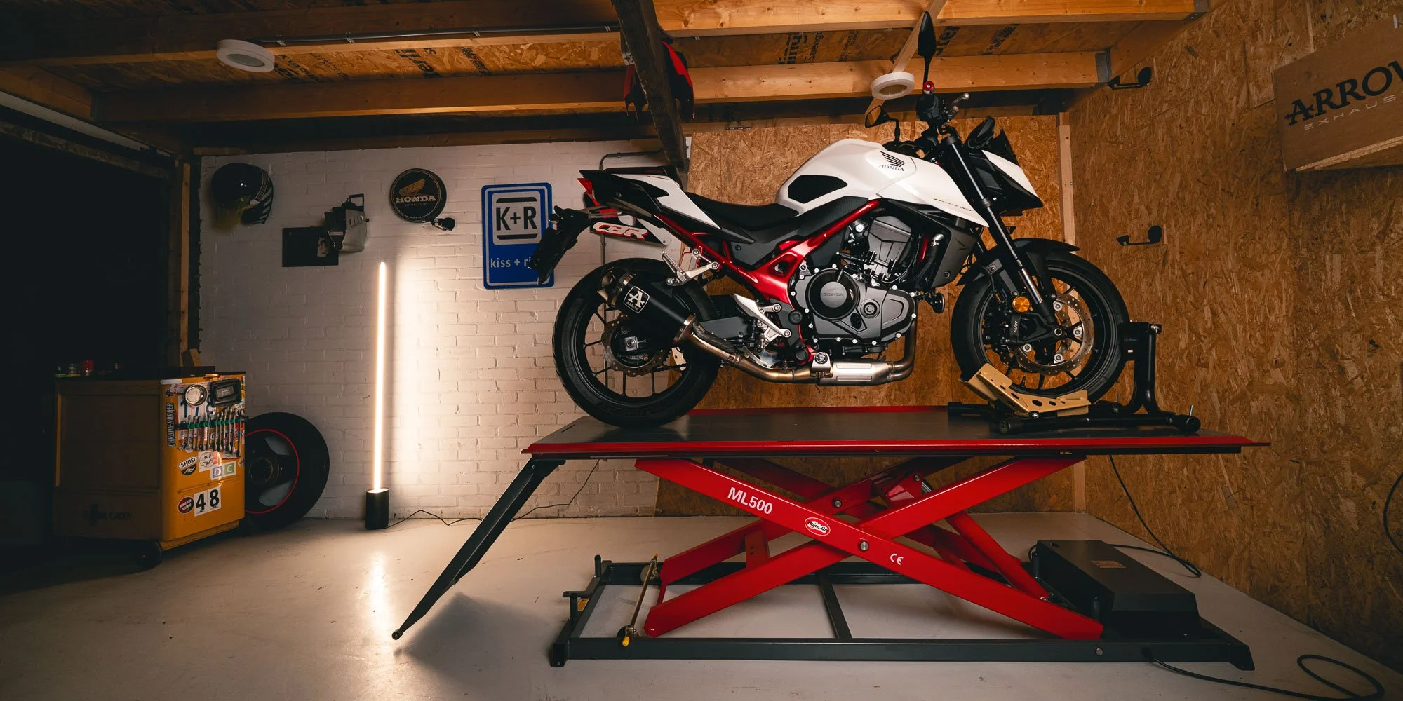 Honda Hornet 750 2025 met arrow uitlaat in een nette garage met motorheftafel mooi verlicht